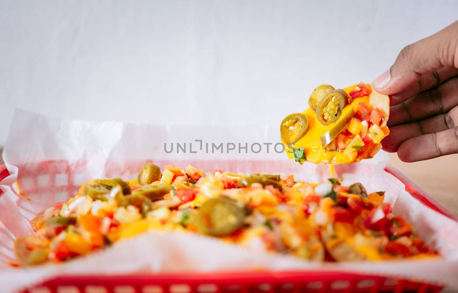 Hand taking nachos from a tray. Hand of people taking nachos on isolated background by isaiphoto