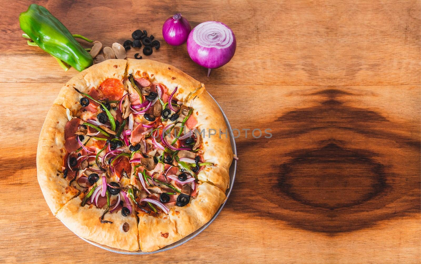 View of supreme pizza with vegetables on wooden background. Top view of supreme pizza with olives and vegetables on wooden table