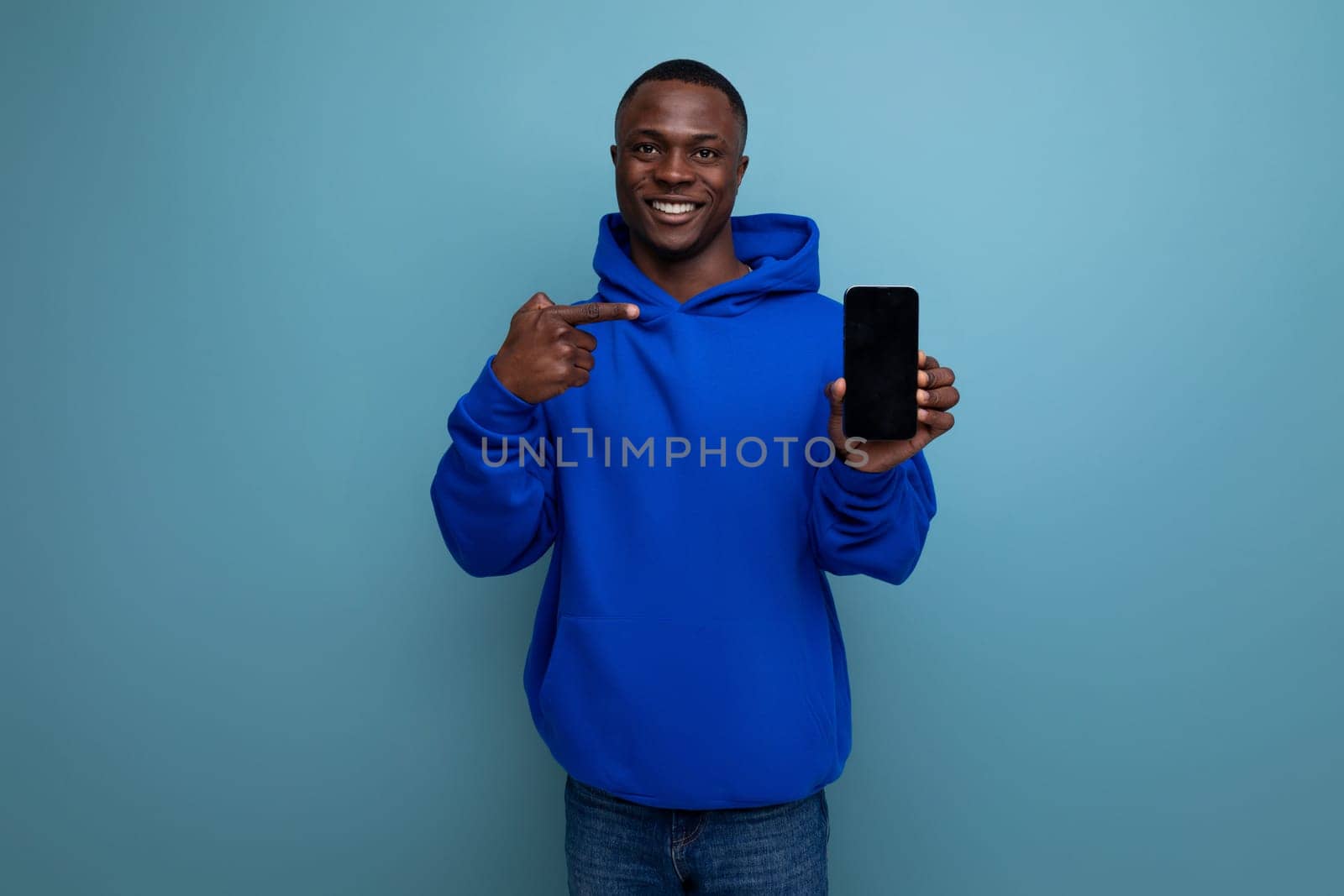 smiling young american consultant man with short haircut holding a smartphone in his hands with a mockup for advertising.