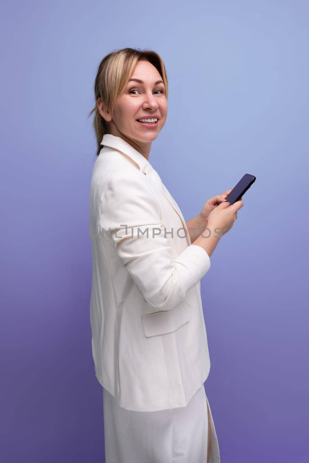 pretty slim young caucasian blondie lady in a white jacket and dress on a plain background.