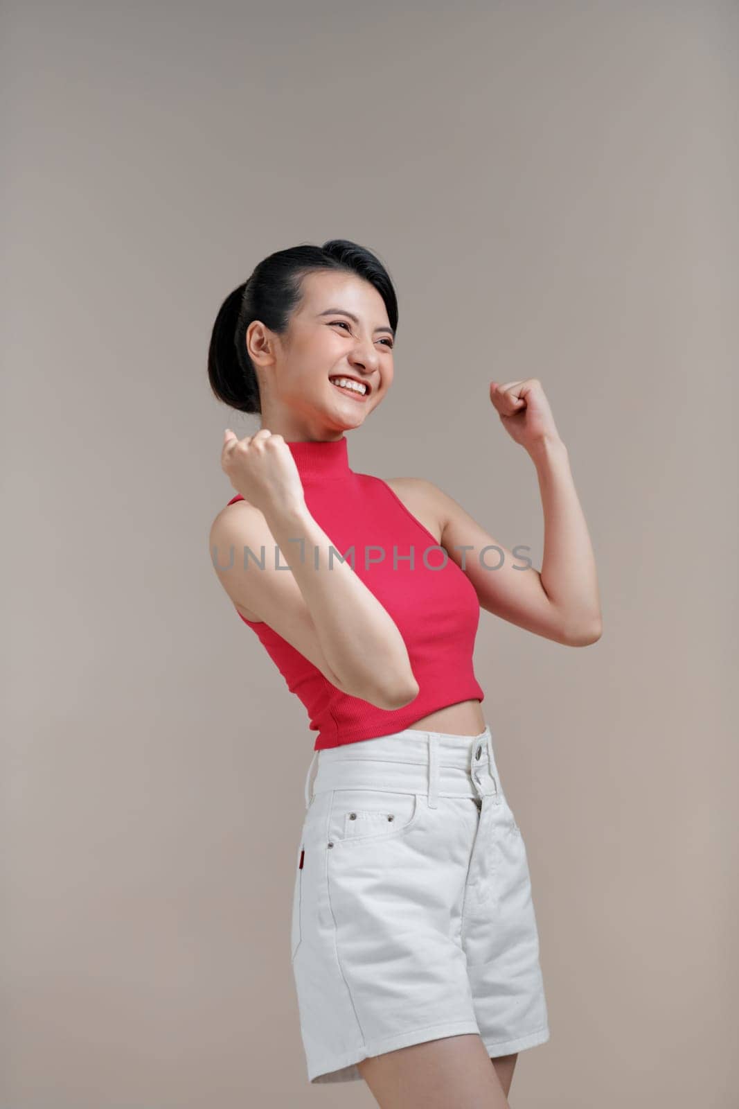 Happy successful young asian female with raised hands celebrating success