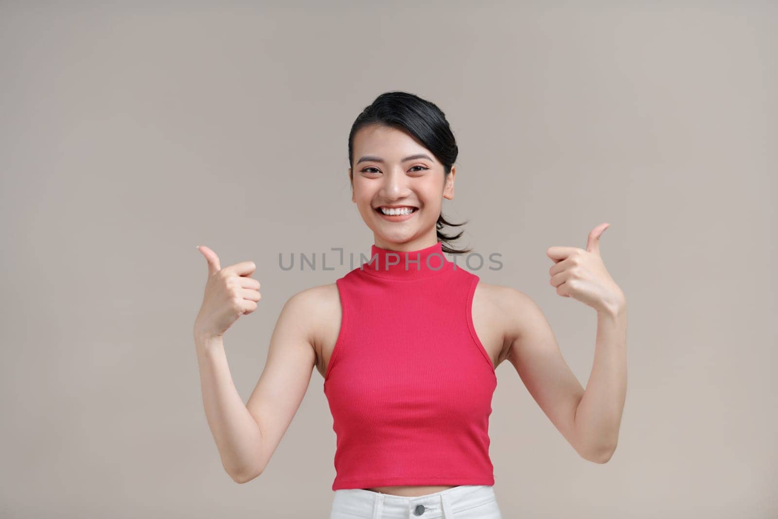 Beautiful young girl smiling and shows thumbs up gesture with two hands