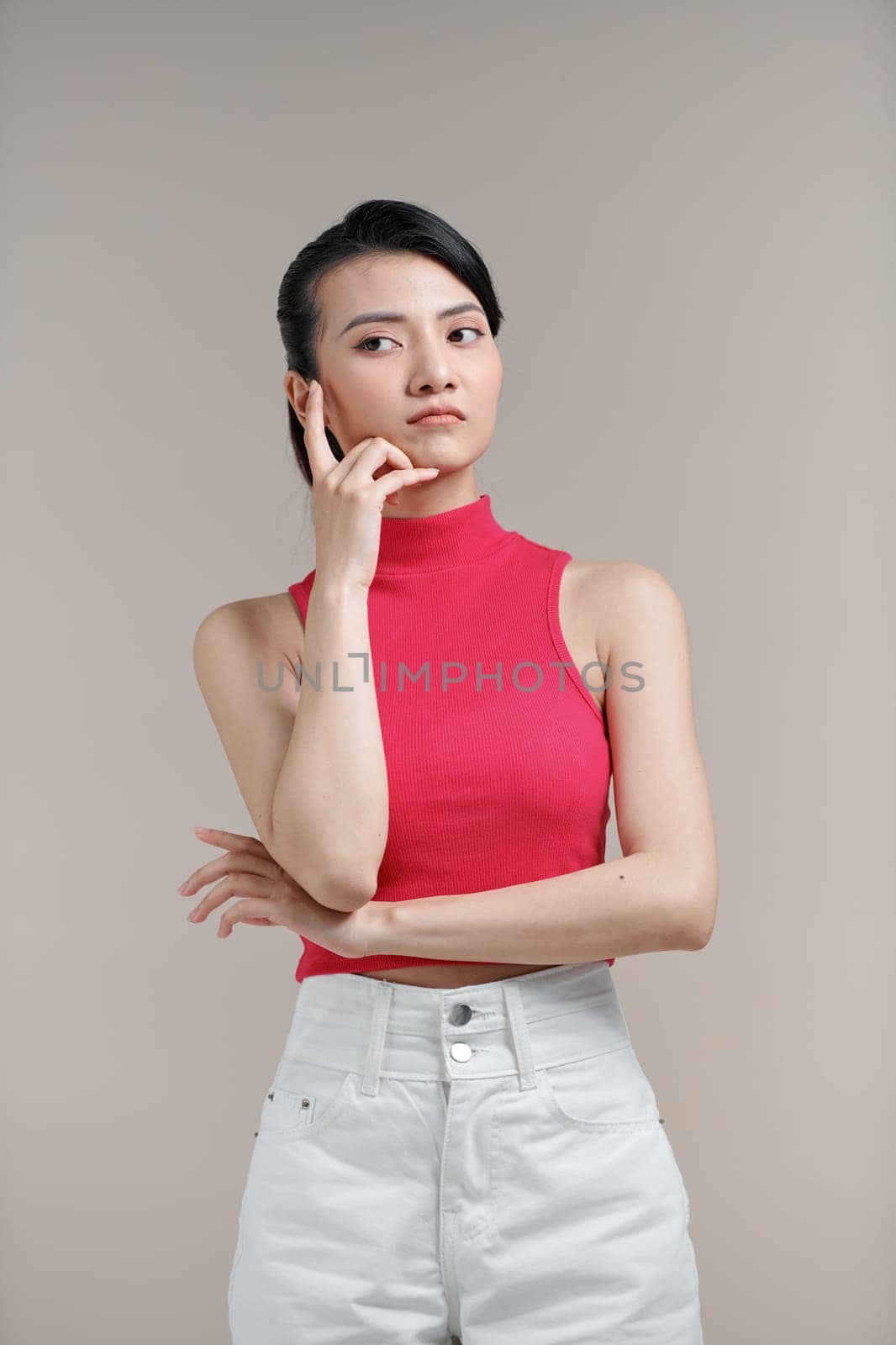 beautiful young asian woman posing with hand on chin thinking isolated on white