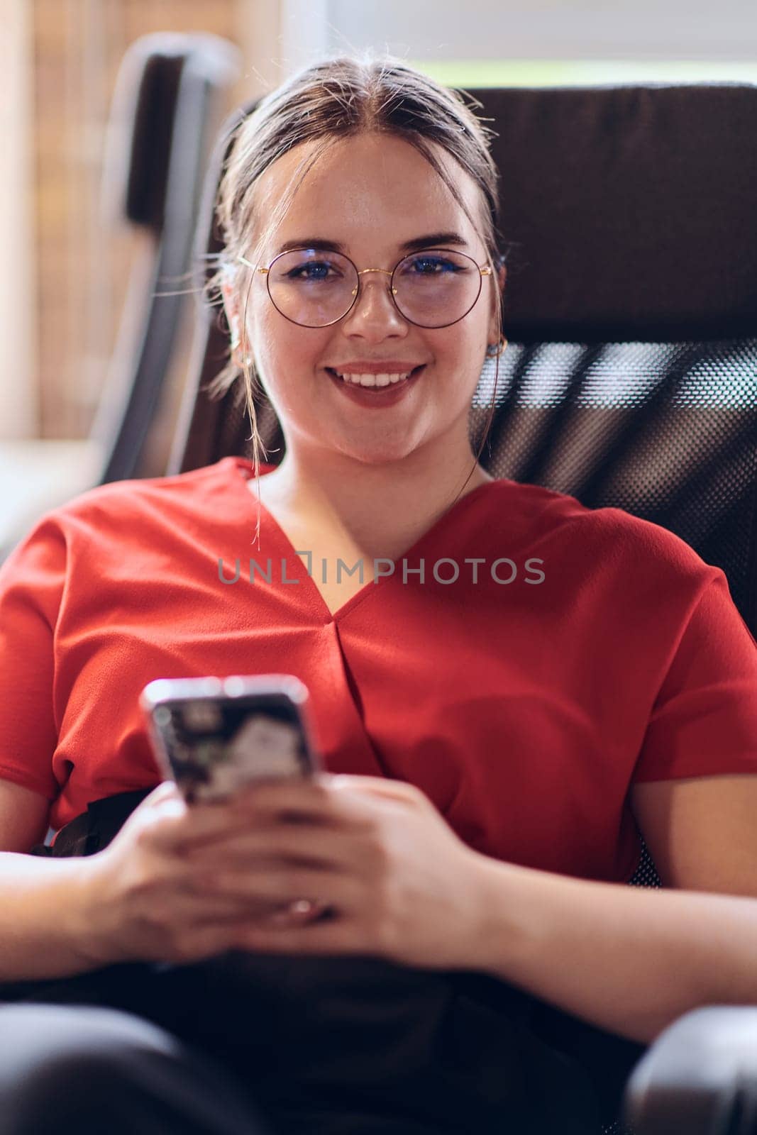 A businesswoman resting on a short break from work in a modern startup coworking center, using her smartphone to unwind and recharge