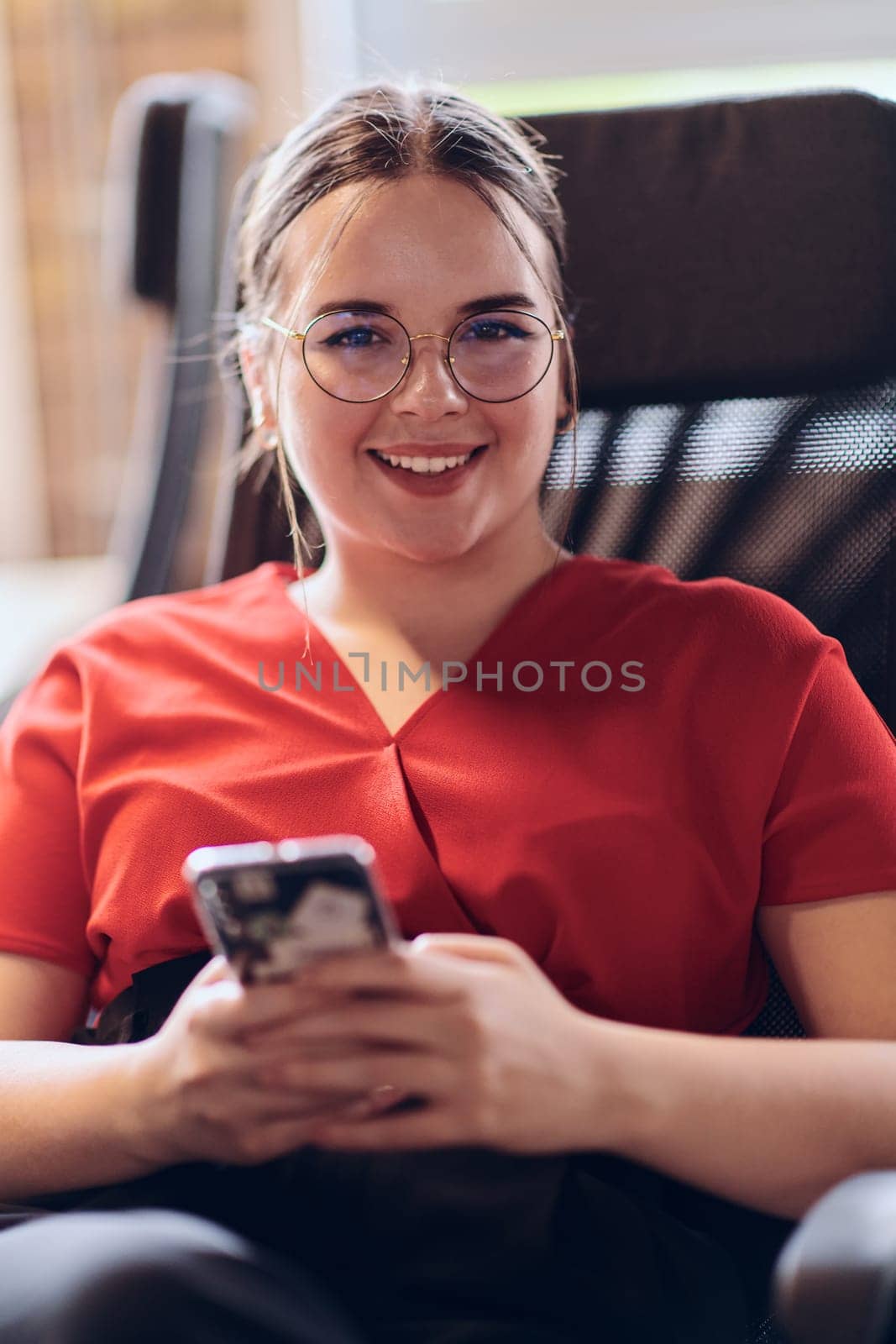 A businesswoman resting on a short break from work in a modern startup coworking center, using her smartphone to unwind and recharge. by dotshock