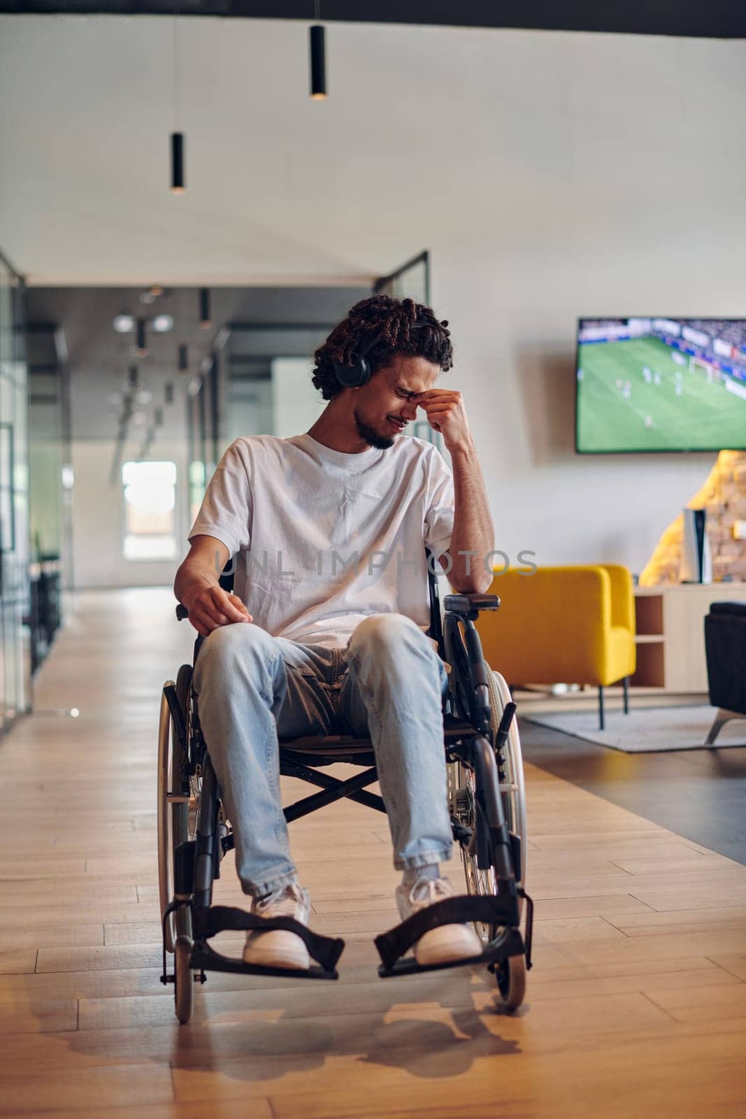 A sad businessman in a wheelchair occupies a hallway within a modern startup coworking center, embodying inclusivity and determination in the business environment.