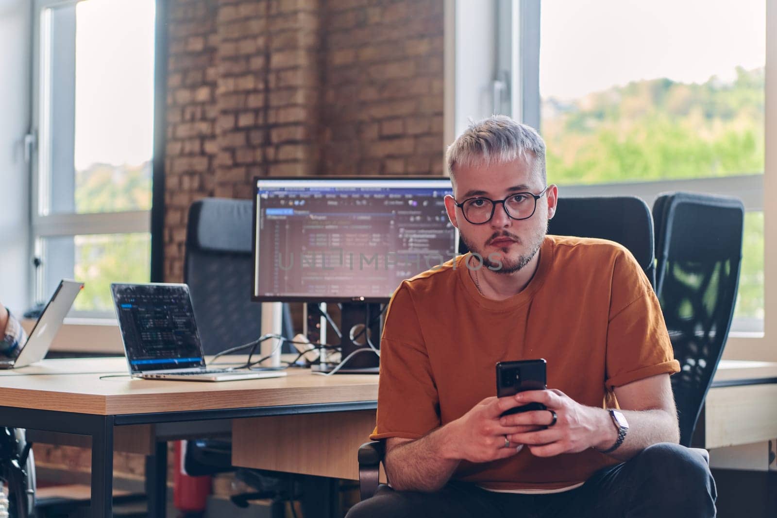 A modern businessman takes a relaxing break from work, using his smartphone to unwind and recharge during his pause.