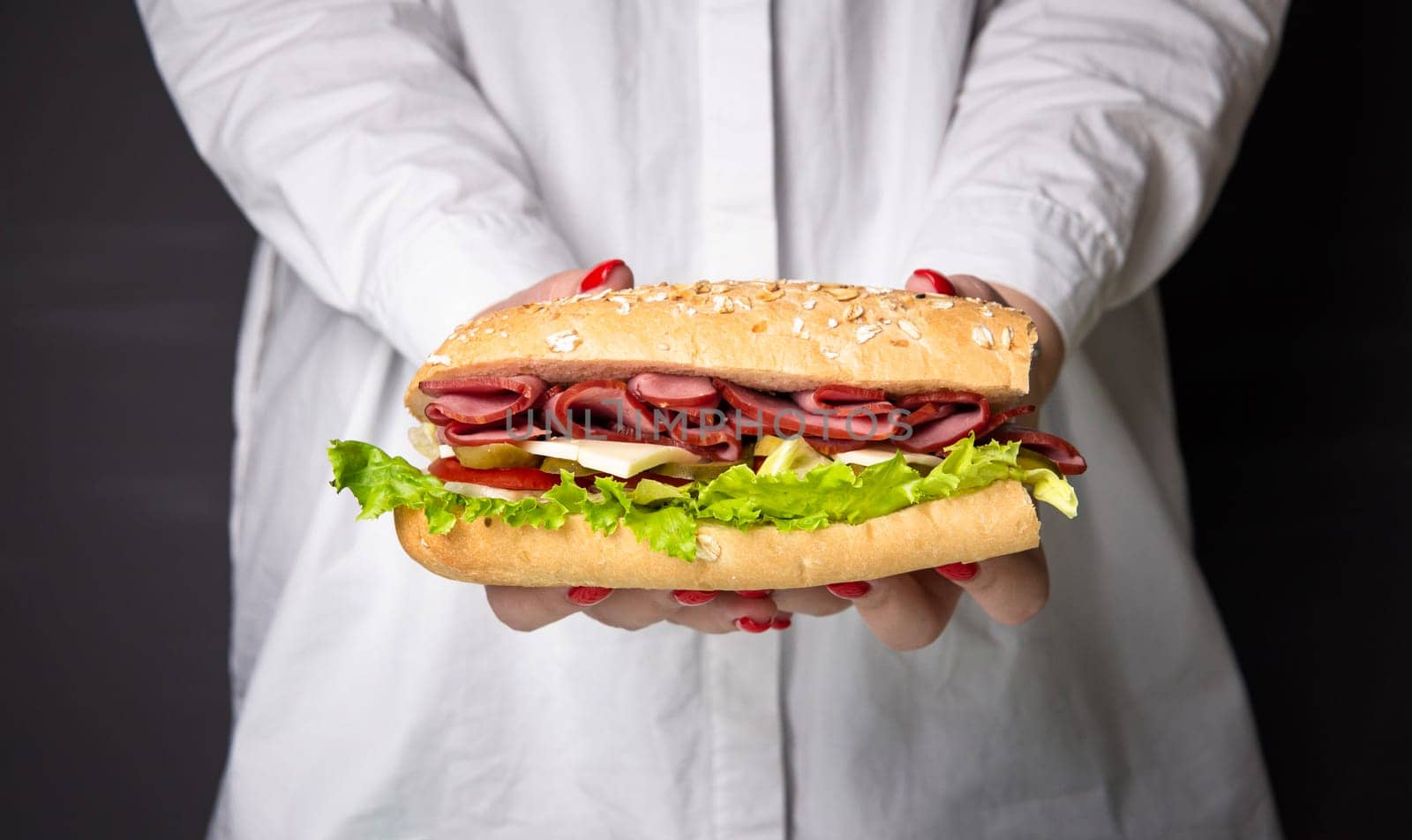 sandwich in women's hands on a black background.