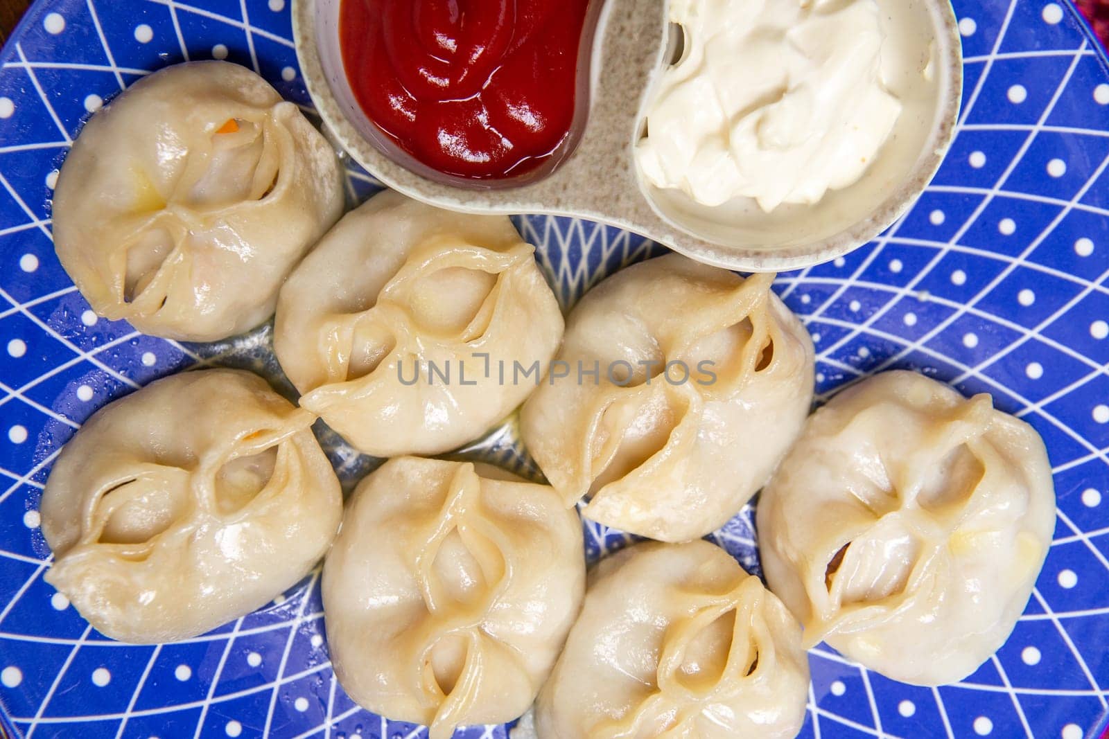 manti and sauce on a blue plate on a burgundy background