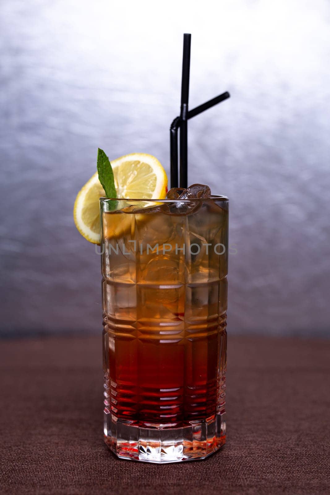 cold alcoholic drink with ice and a slice of lemon in a glass glass with a straw.