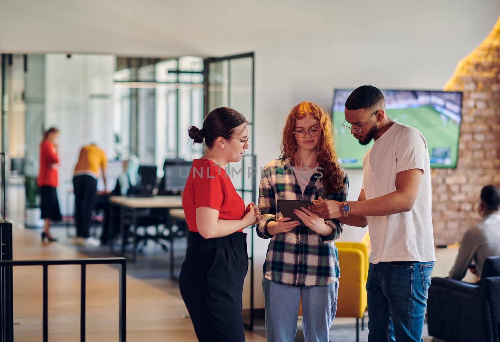 A group of young business individuals, including a girl with orange hair and an African American man, stands in a modern corporate hallway, collectively examining business progress on a smartphone, exemplifying dynamic collaboration and digital engagement. by dotshock