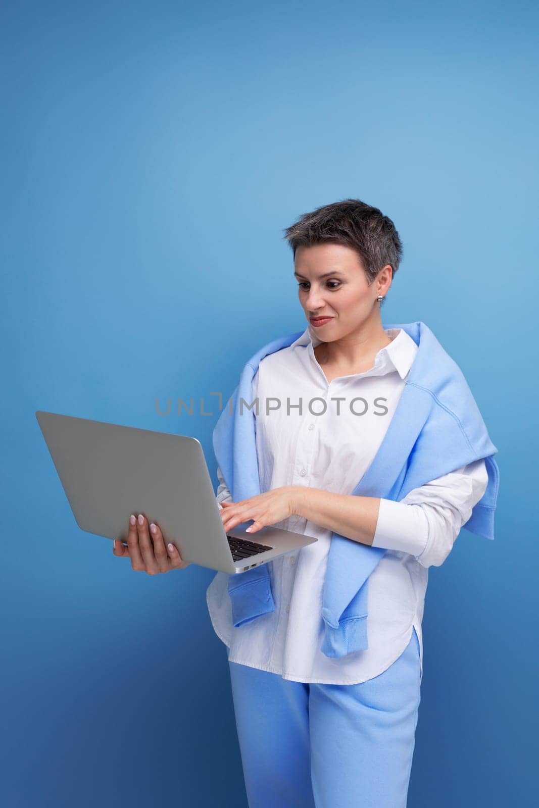 european young brunette woman with tousled hair works remotely using laptop.