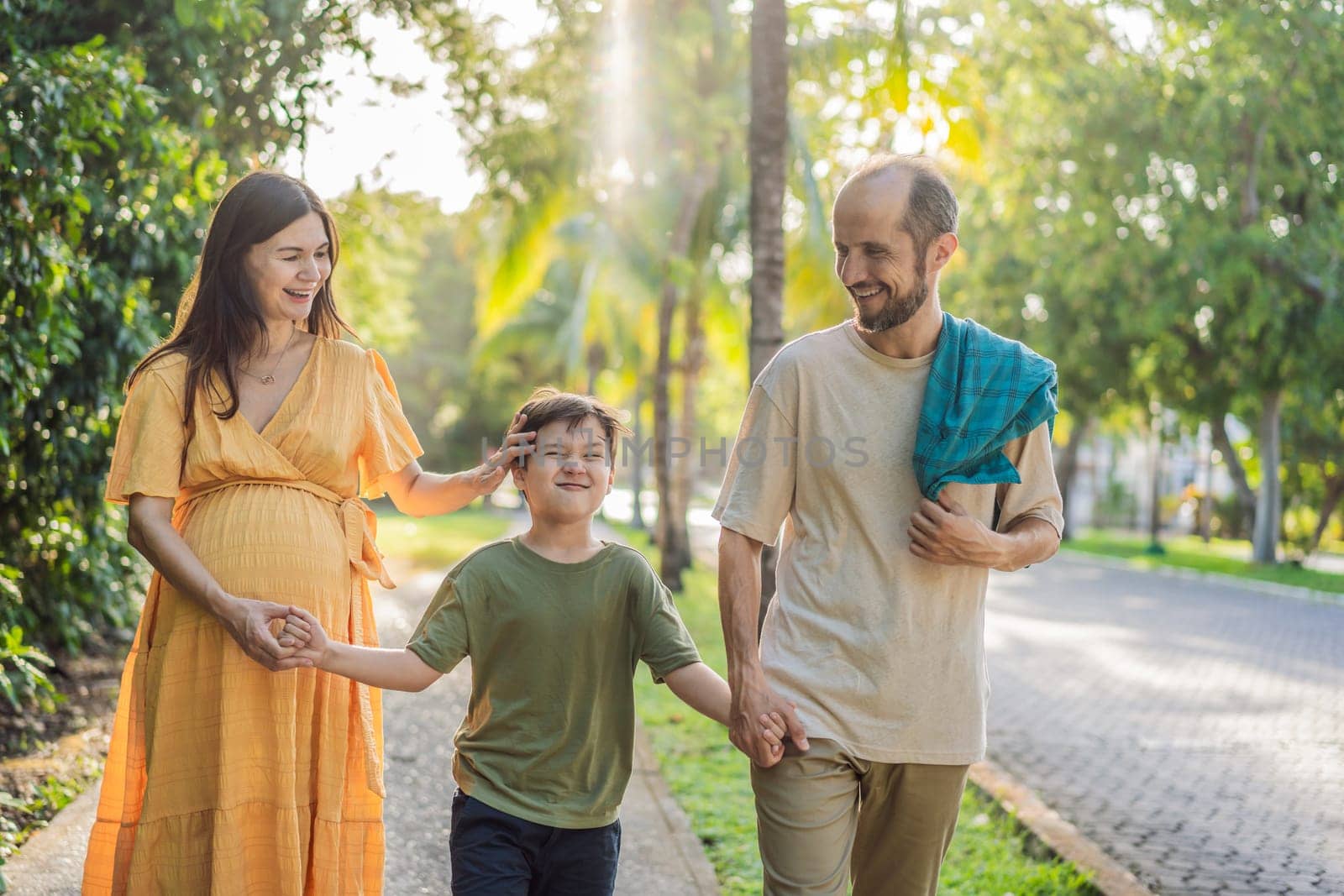 A loving family enjoying a leisurely walk in the park - a radiant pregnant woman after 40, embraced by her husband, and accompanied by their adult teenage son, savoring precious moments together amidst nature's beauty. Pregnancy after 40 concept.