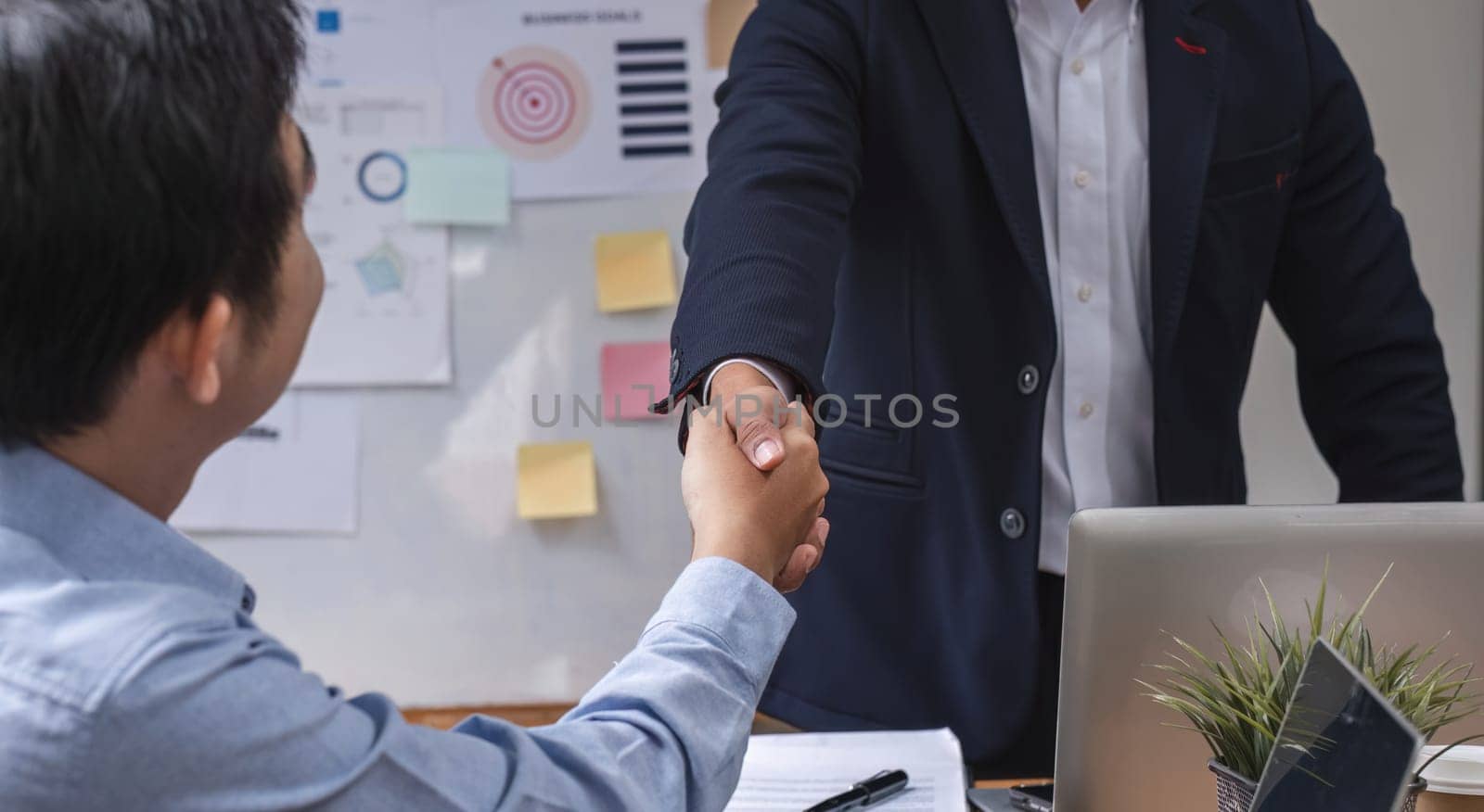 close up, Two happy professional businessmen shaking hands after a successful financial deal at a meeting. by wichayada