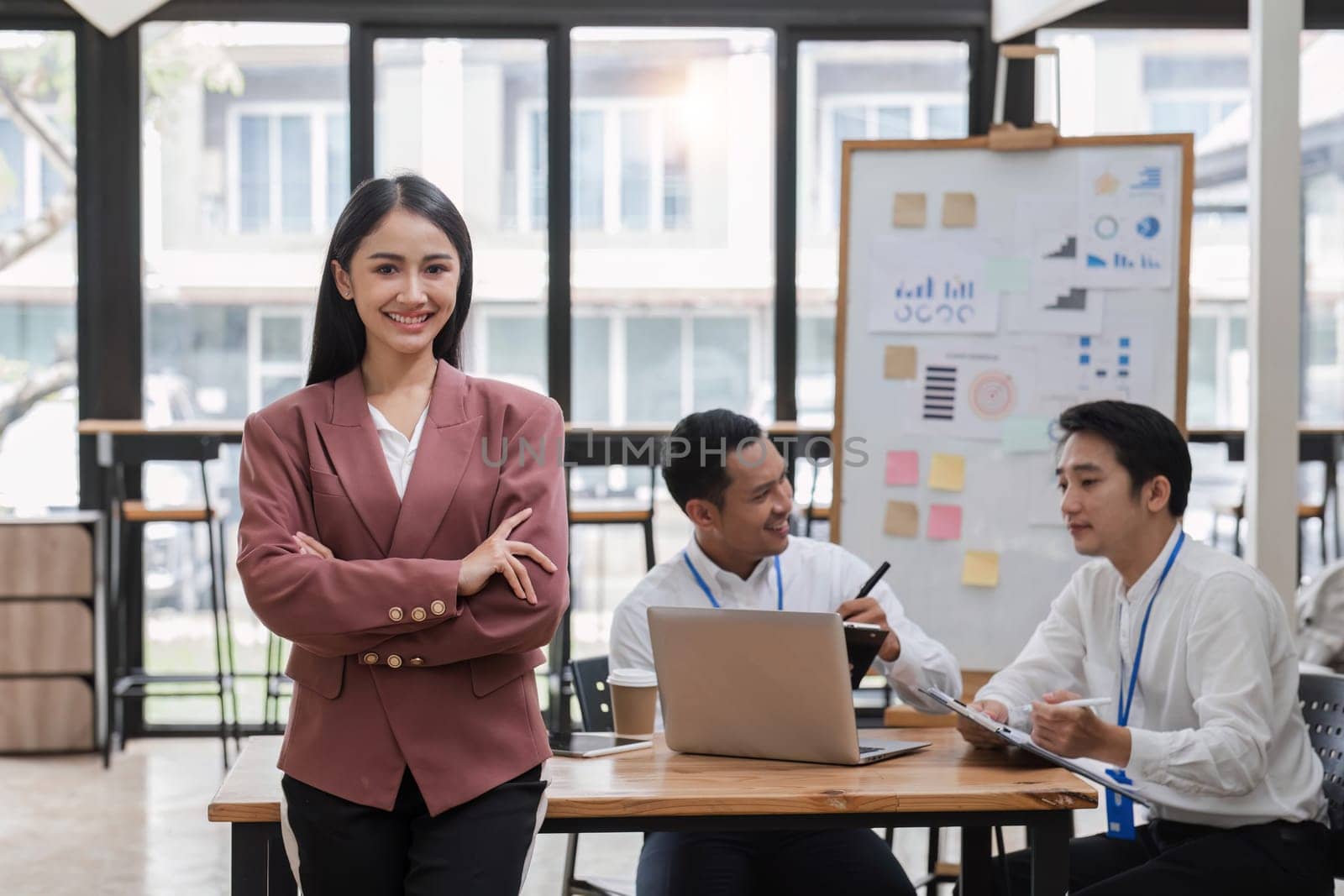 Portrait of a young businesswoman standing in an office where employees are working..