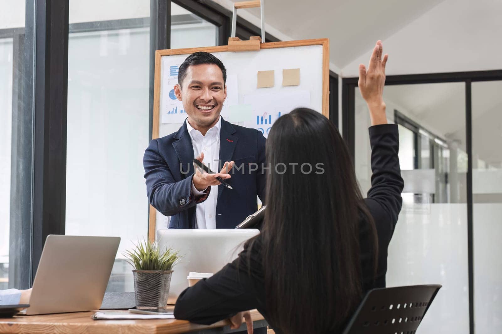 colleagues asking a question to a businessman during a presentation. by wichayada