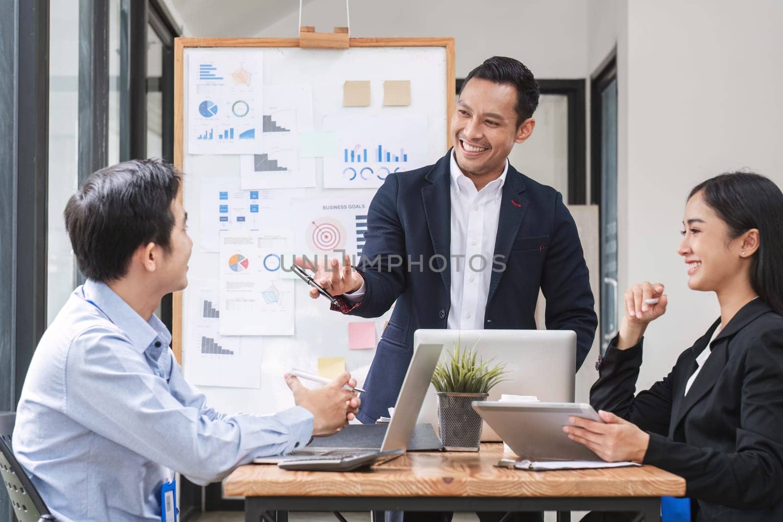 Professional businessman presenting to colleagues in conference room explaining growth chart.