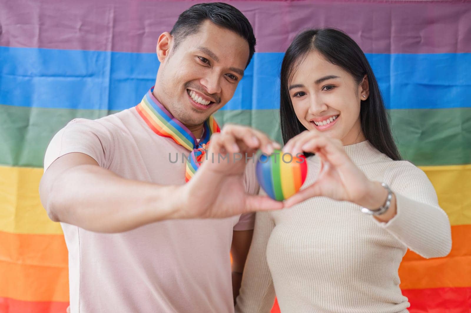 Men and women hold rainbow hearts, a symbol of the LGBT community, in support of gender equality..
