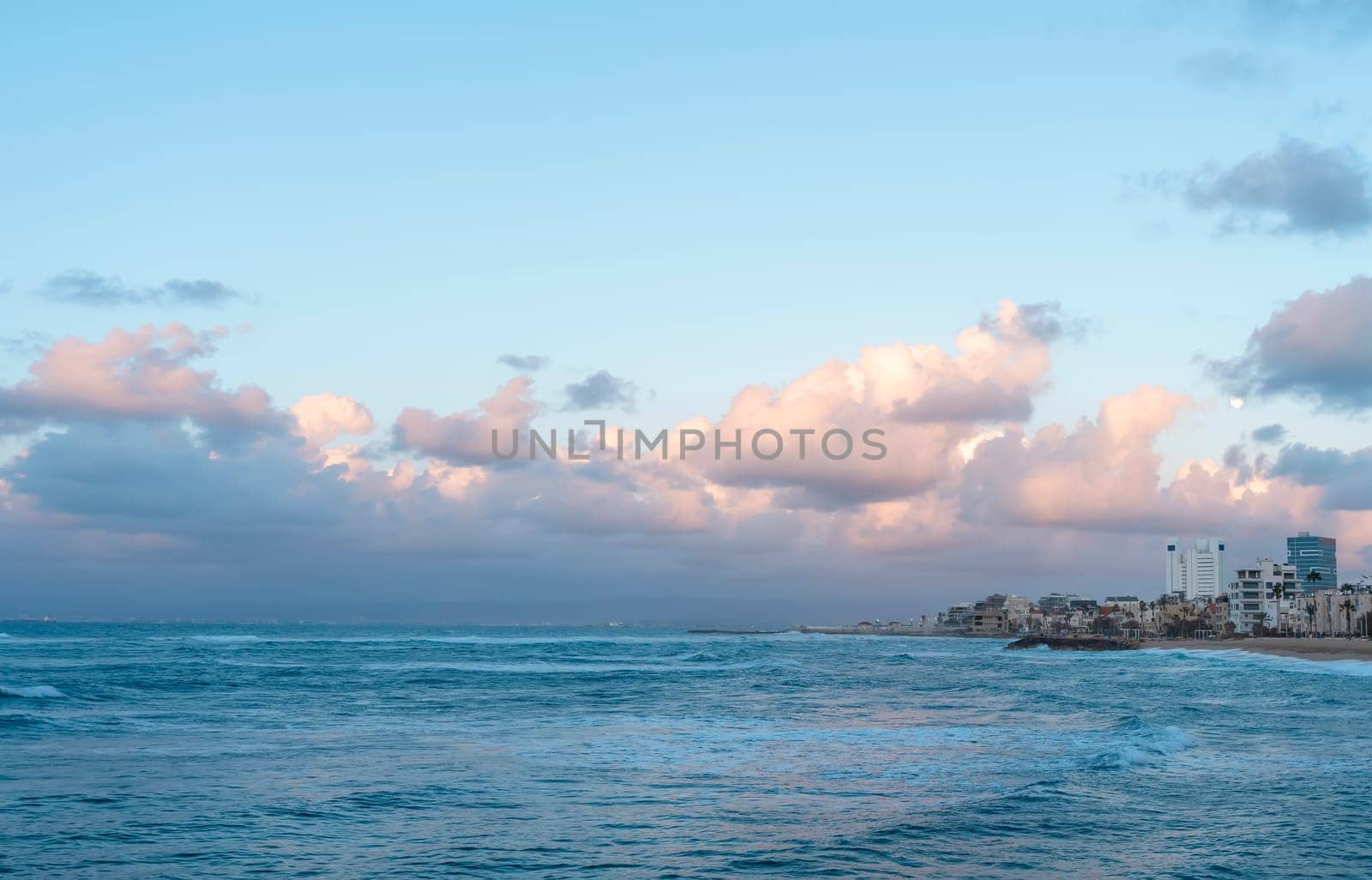 Amazing view of the costal city, sand beach, sea and cloudy blue sky at sunset by Iryna_Melnyk