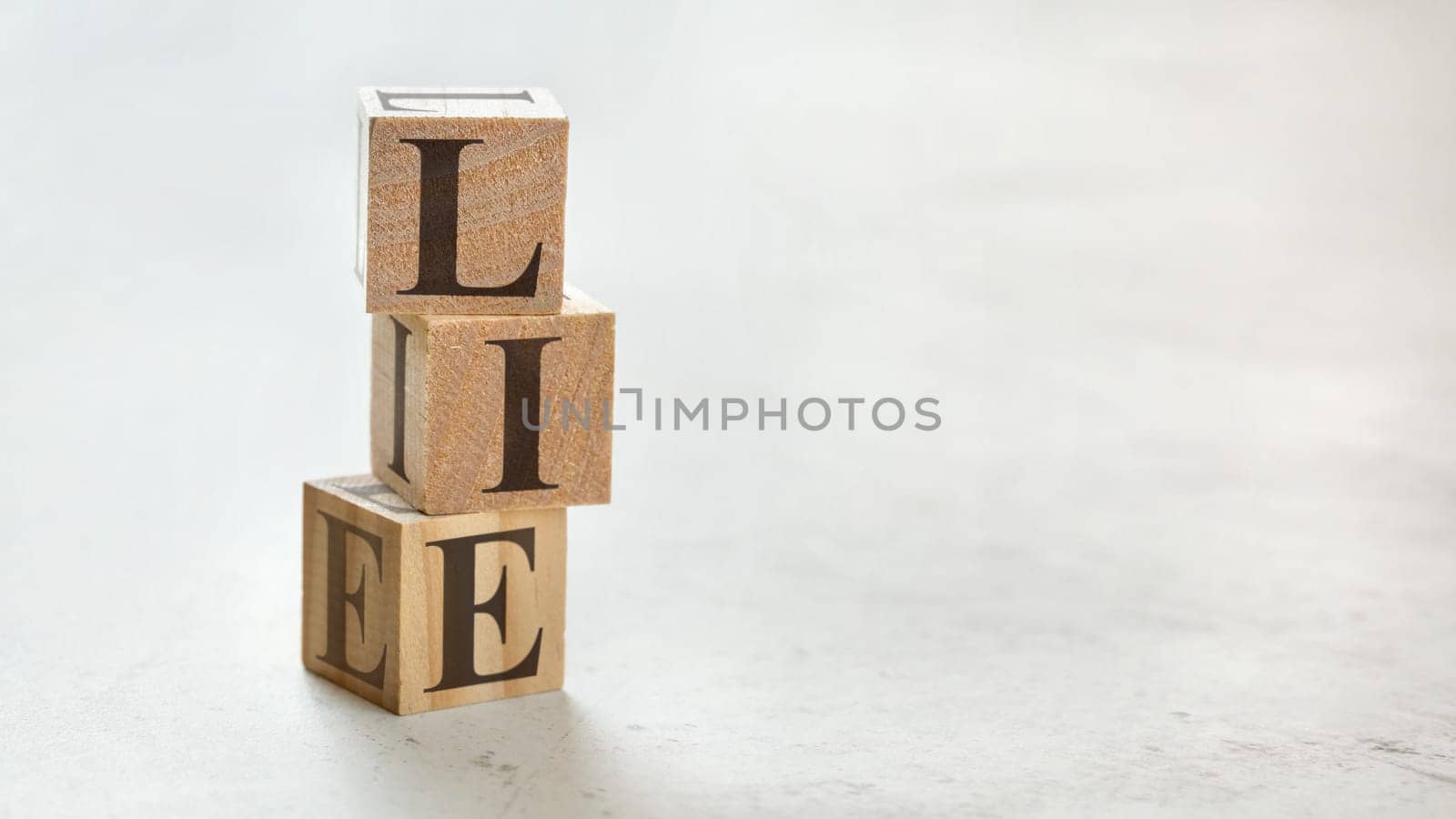 Pile with three wooden cubes - word LIE on them, space for more text / images at right side.