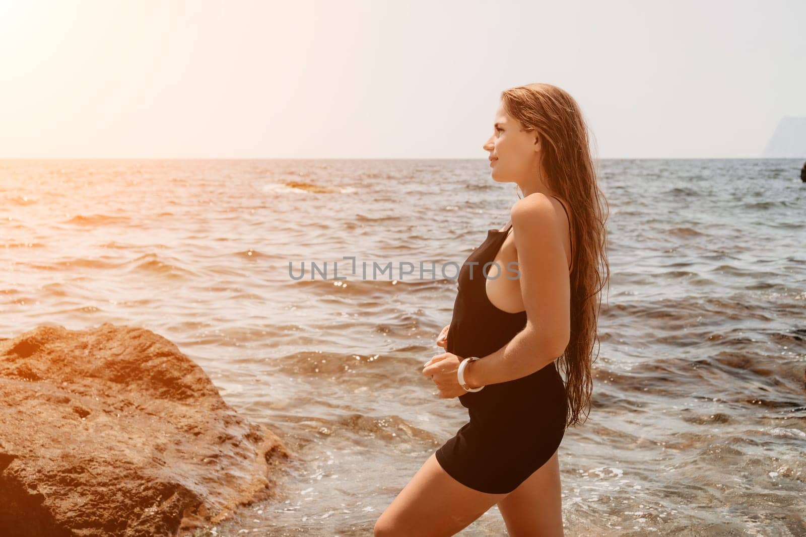 Woman summer travel sea. Happy tourist in hat enjoy taking picture outdoors for memories. Woman traveler posing on the beach at sea surrounded by volcanic mountains, sharing travel adventure journey by panophotograph