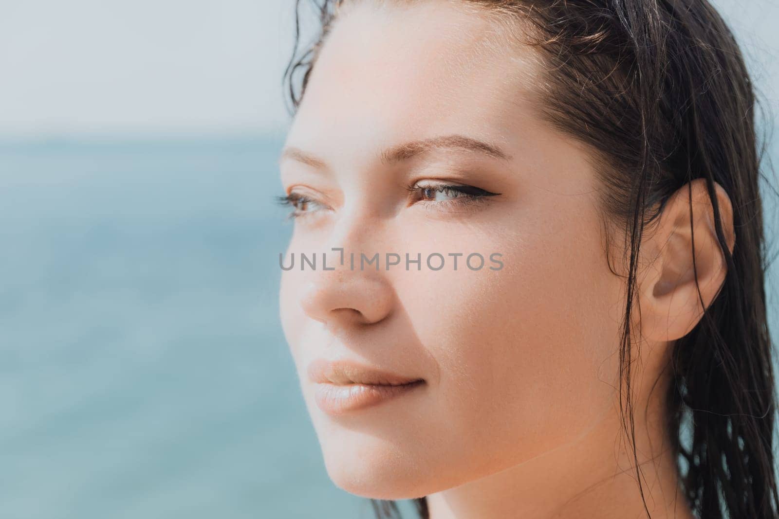 Woman sea sup. Close up portrait of beautiful young caucasian woman with black hair and freckles looking at camera and smiling. Cute woman portrait in a pink bikini posing on sup board in the sea by panophotograph