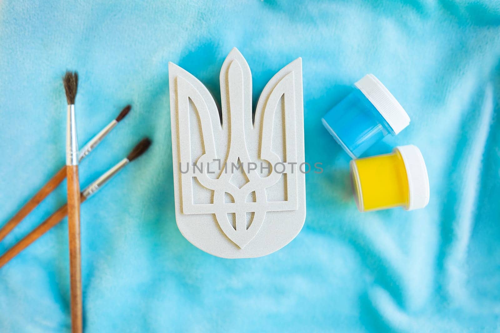 The State Emblem of Ukraine on a plaster form on a blue background, yellow-blue paints, paint the coat of arms