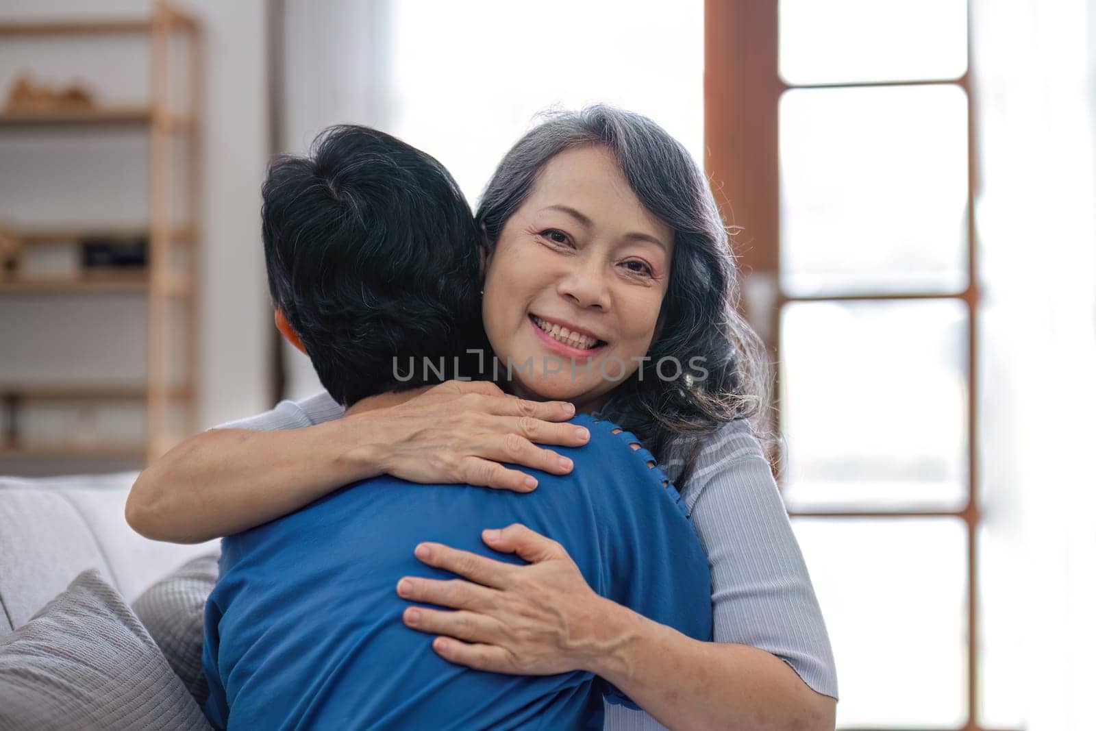 Two retired Asian women hug as they meet and have fun in the living room..