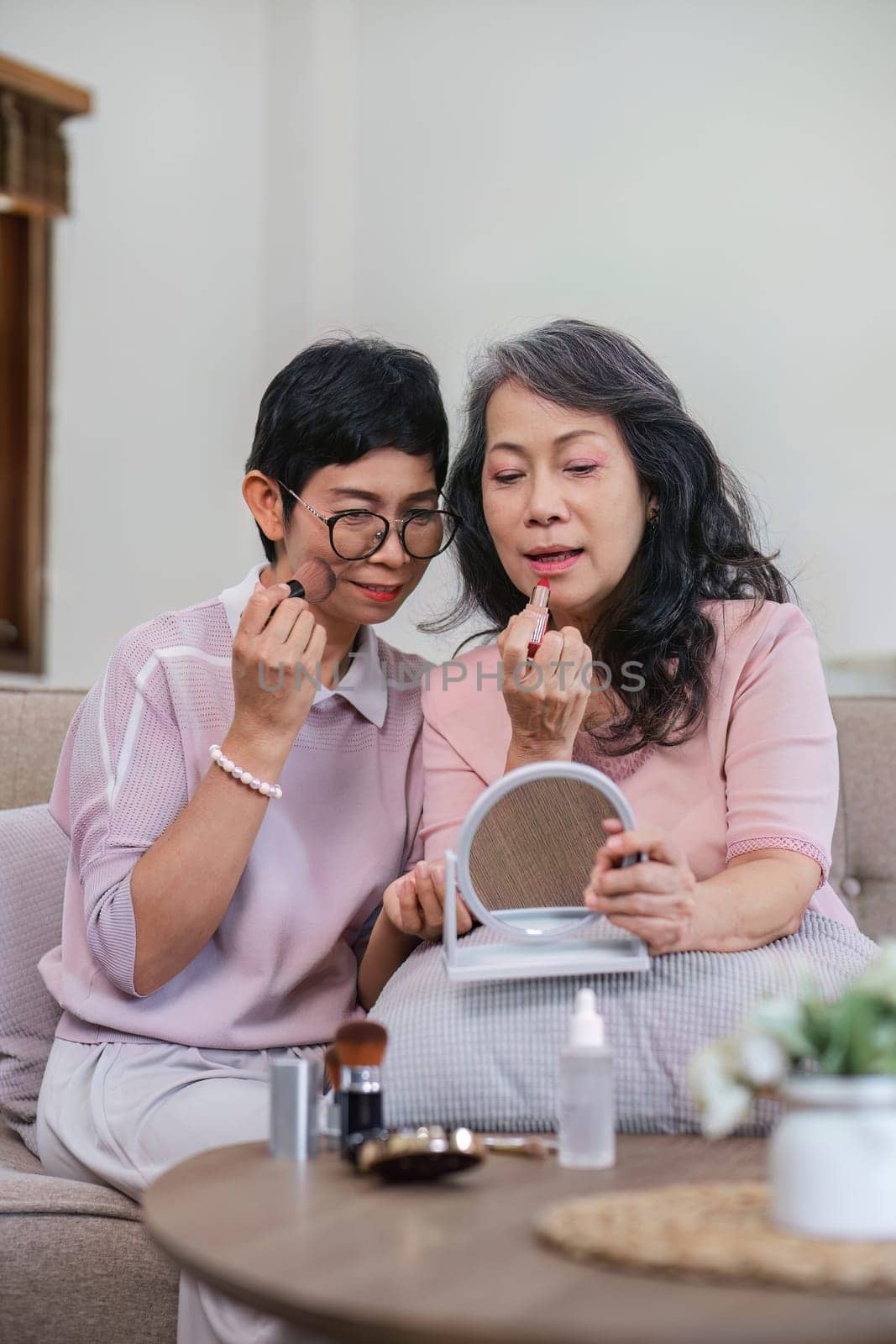 An elderly woman happily spends her free time make up with friends in the living room..