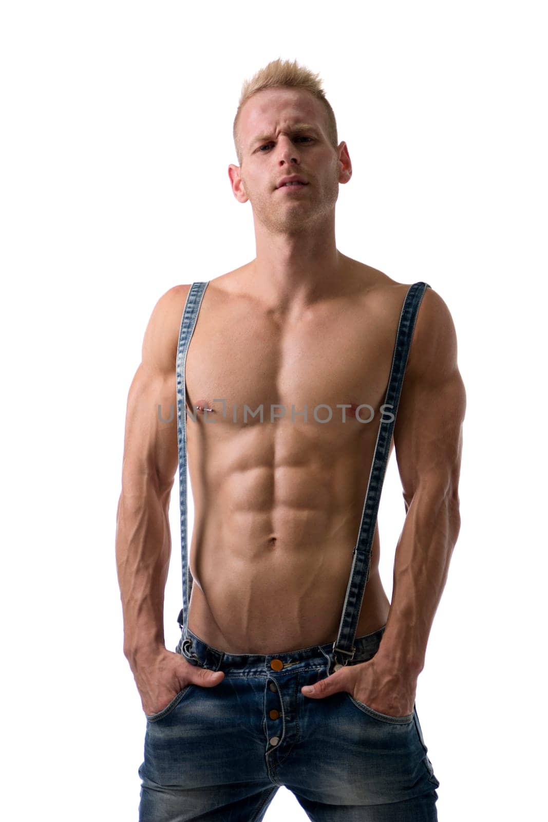 A shirtless man wearing a pair of jeans and suspenders, looking at camera, with muscular body