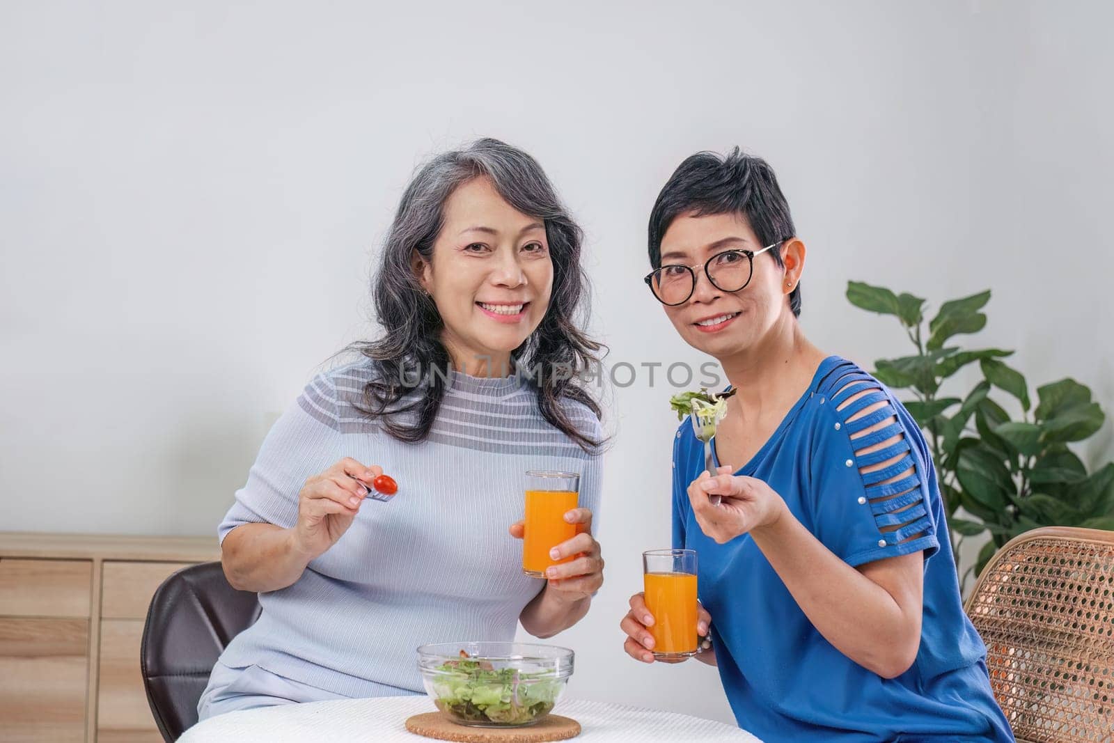 Two Asian woman enjoys talking with her friends while having a healthy food together. by wichayada