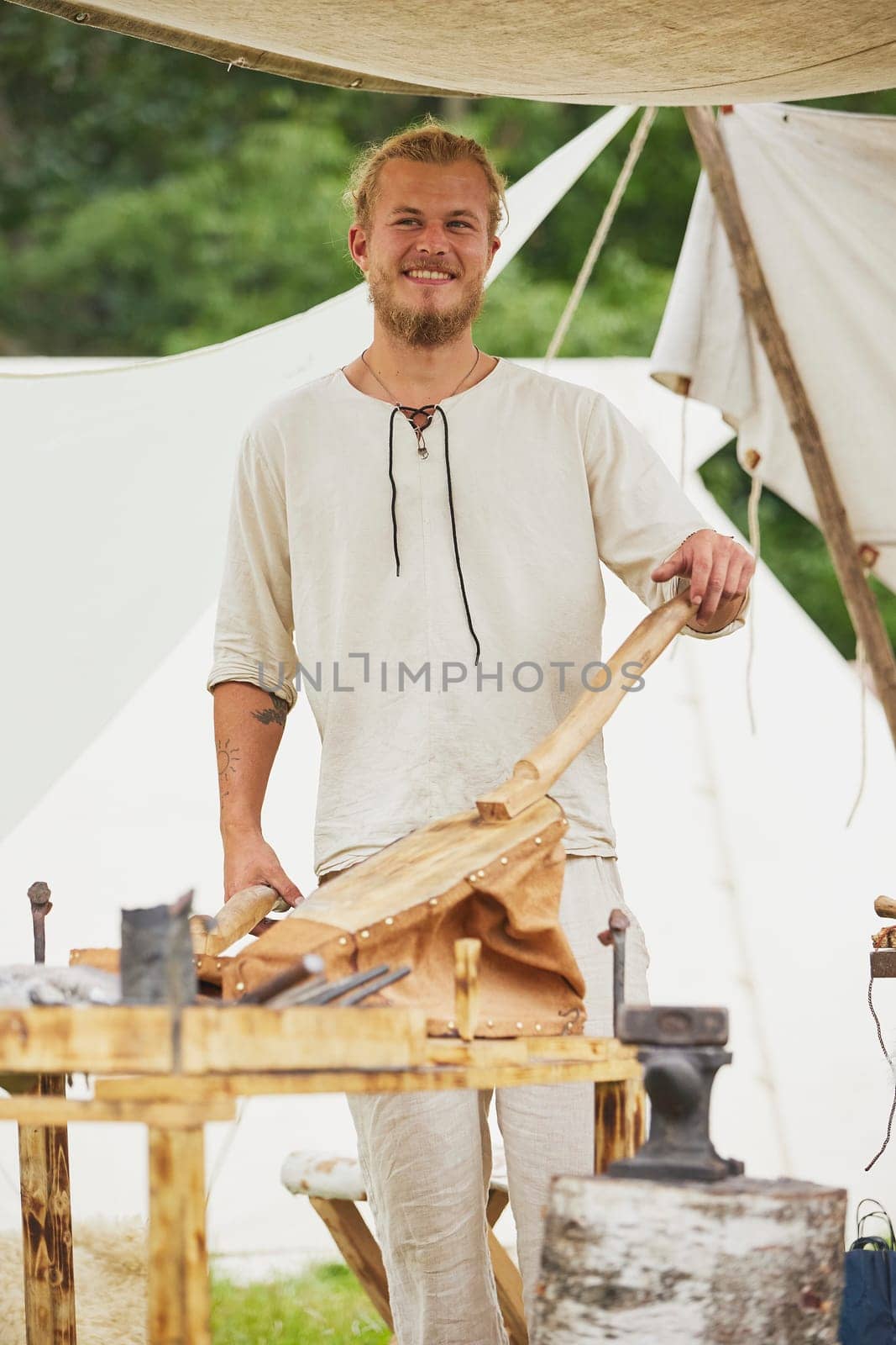 Hojbjerg, Denmark, July 29, 2023: The blacksmith warms up the fire at the Viking festival by Viktor_Osypenko