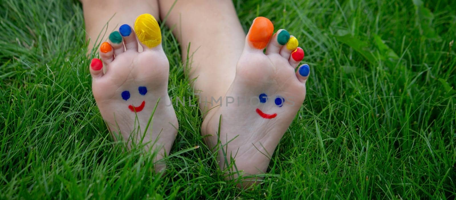 a boy on the grass with a painted smile on his feet.. Selective focus. nature