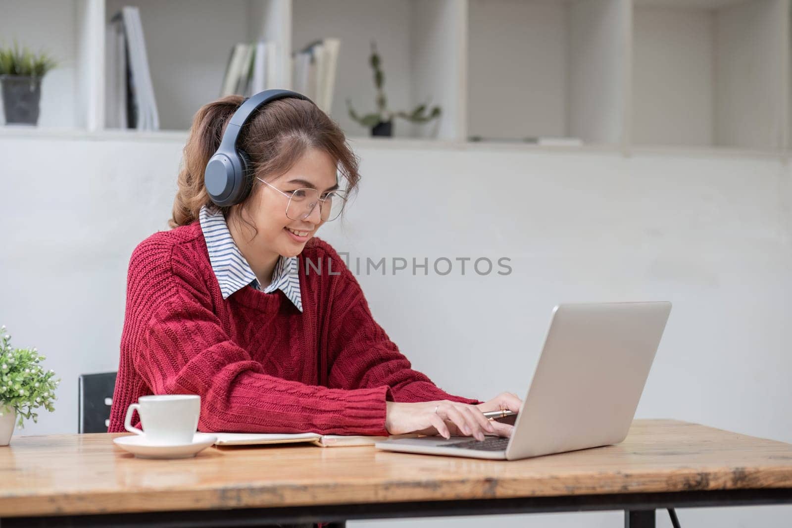 Asian female student study online in class, study online, wearing headphones, watching video call, zooming, happy asian female learning language online with computer laptop. by wichayada