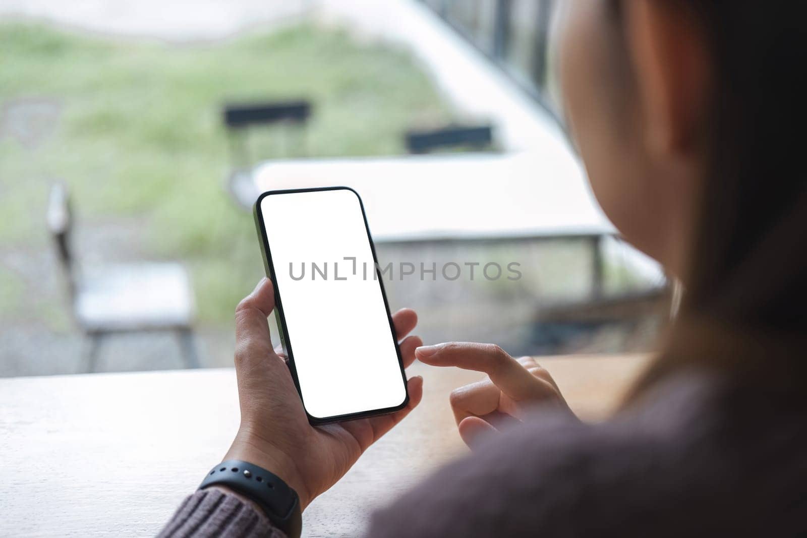 Mockup image of closeup woman hand holding mobile phone with blank white smartphone screen at the outdoor. by wichayada