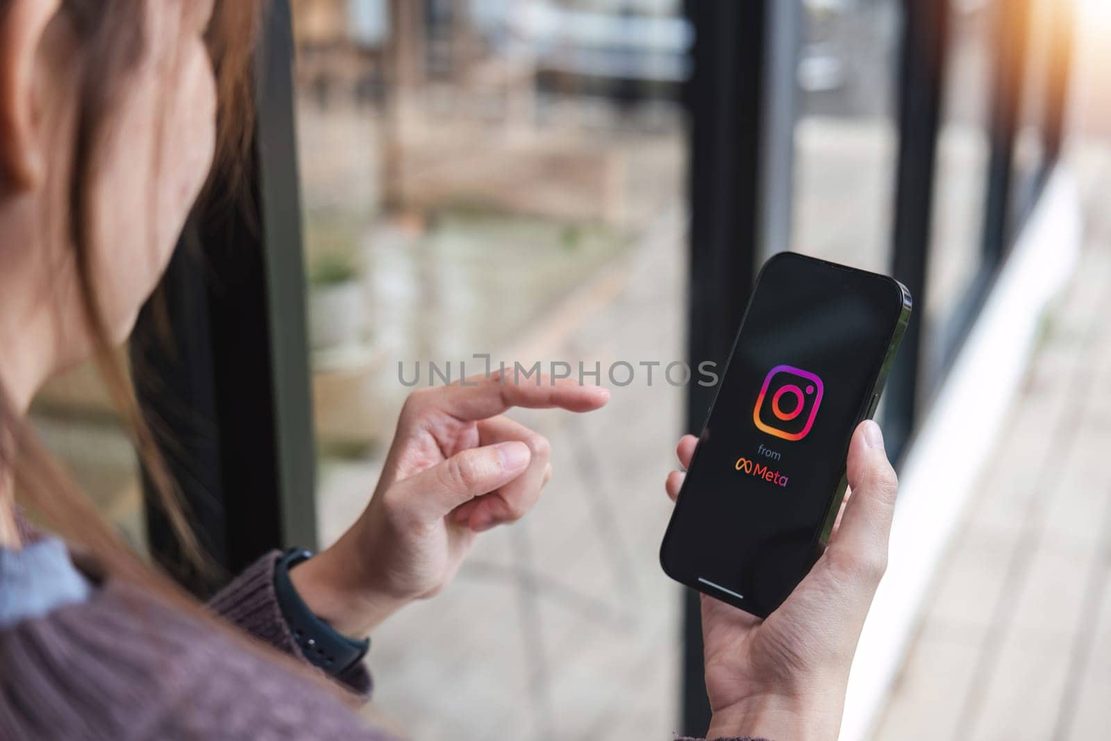 CHIANG MAI, THAILAND - JUL 7, 2023: A woman holds Apple iPhone X with Instagram application on the screen at cafe. Instagram is a photo sharing app for smartphones. by wichayada