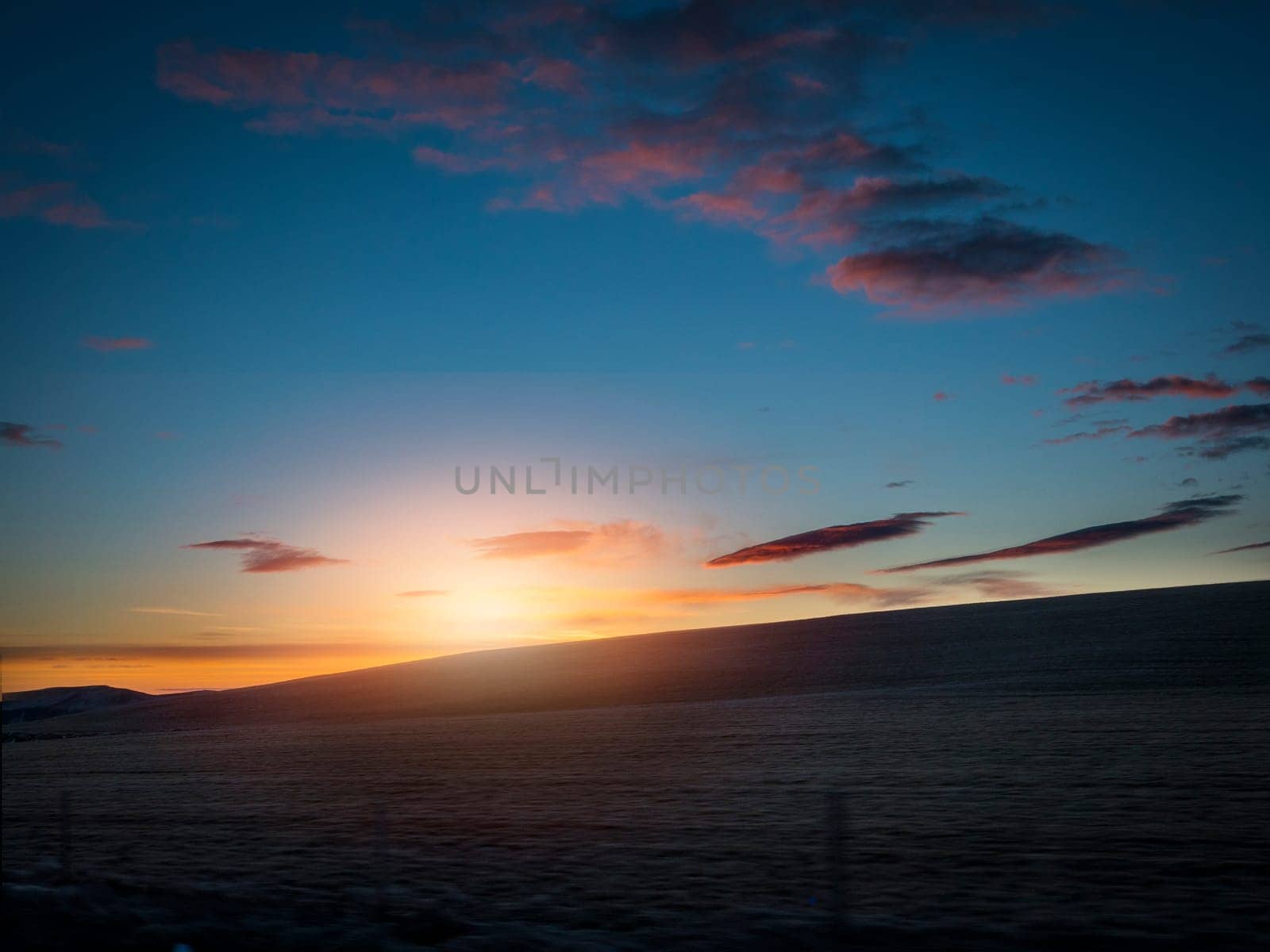 The sun is setting over a body of water. Photo of a beautiful sunset over a serene Icelandic body of water