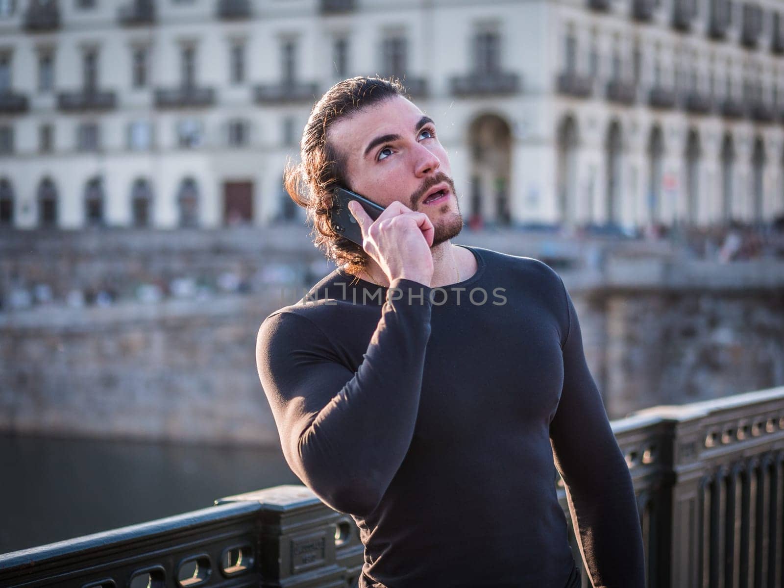 A man standing on a bridge talking on a cell phone