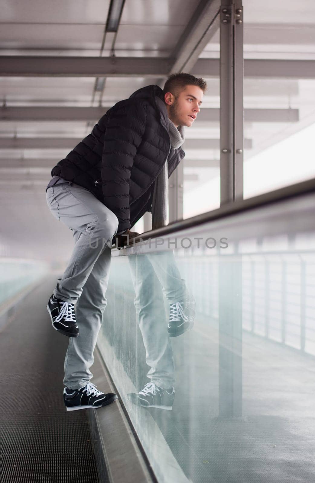 A man leaning against a glass wall in a building