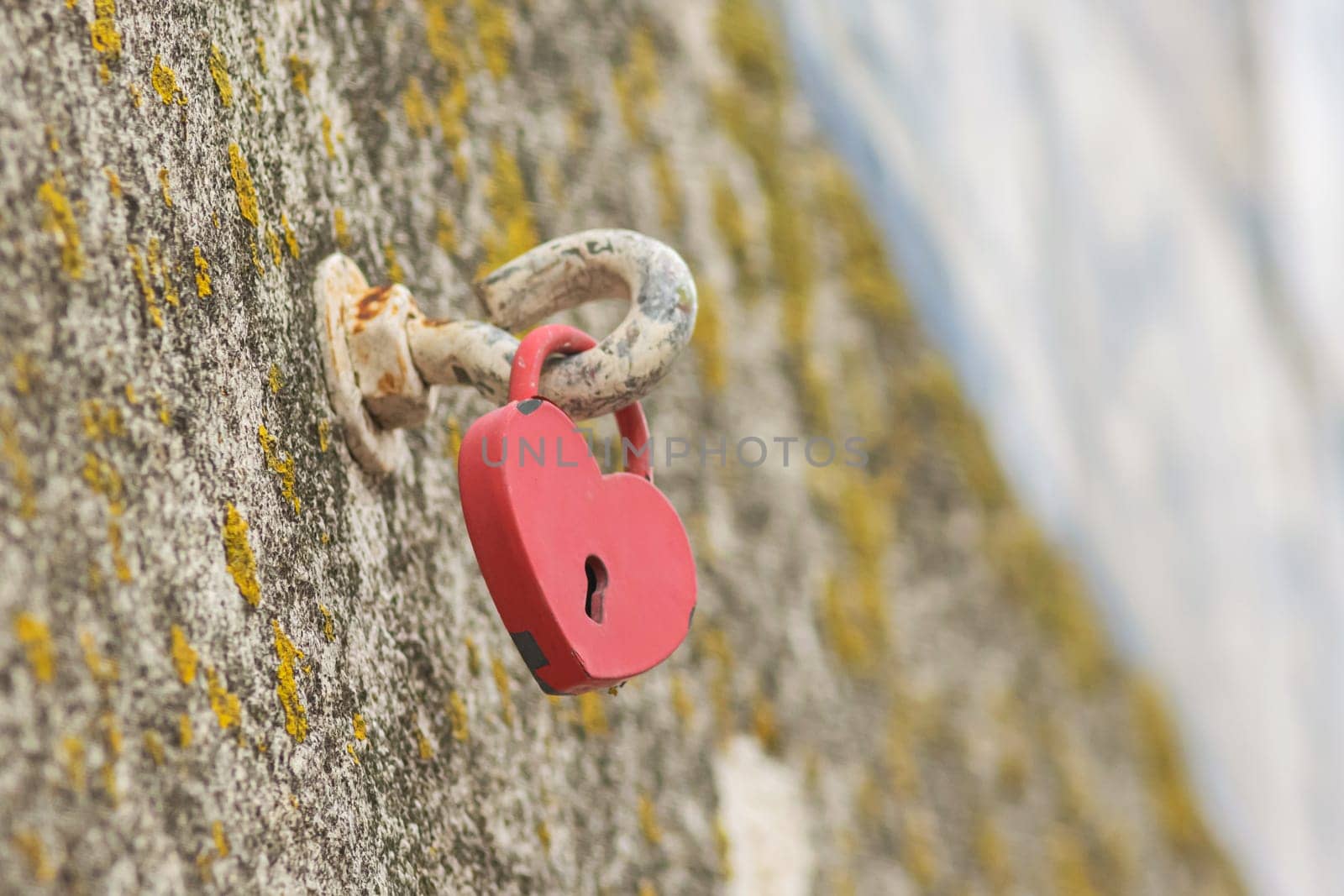 A heart-shaped lock is suspended on a hook. Mid shot