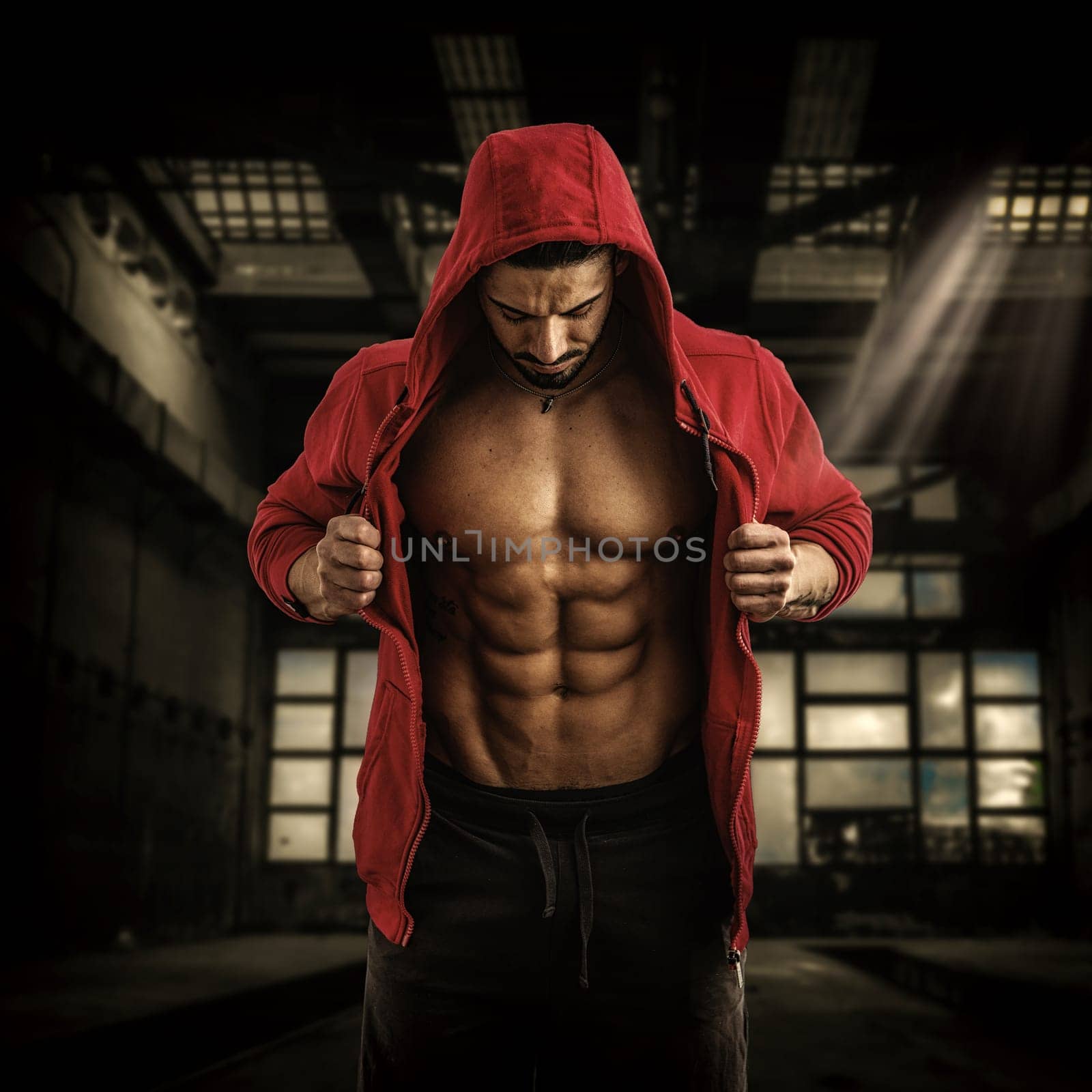 A shirtless man in a red jacket and black pants