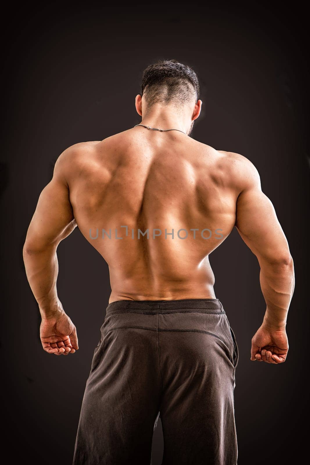 A man with his back turned to the camera, against black background in studio