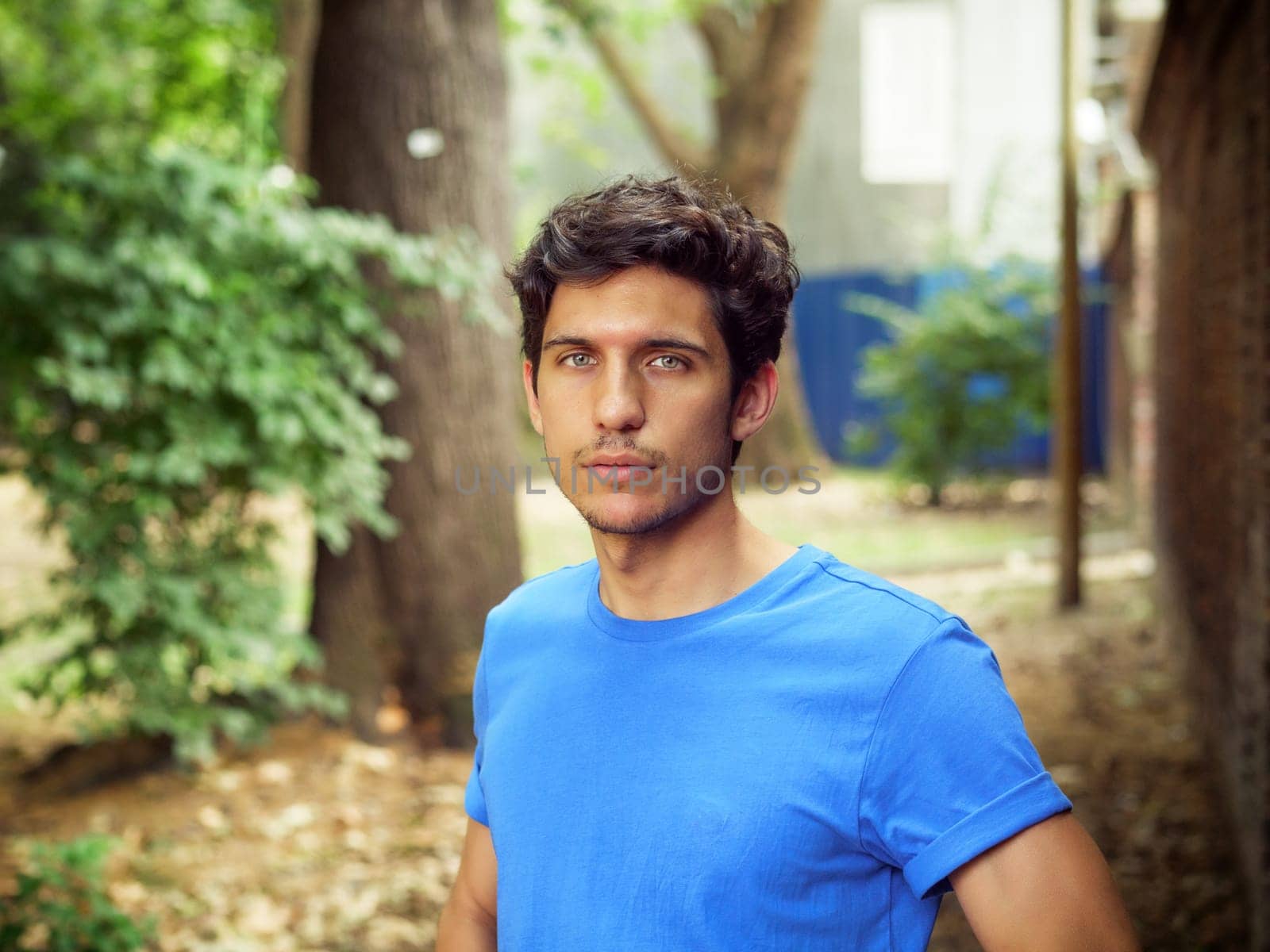 Three quarters shot of one handsome young man in urban setting wearing blue polo shirt