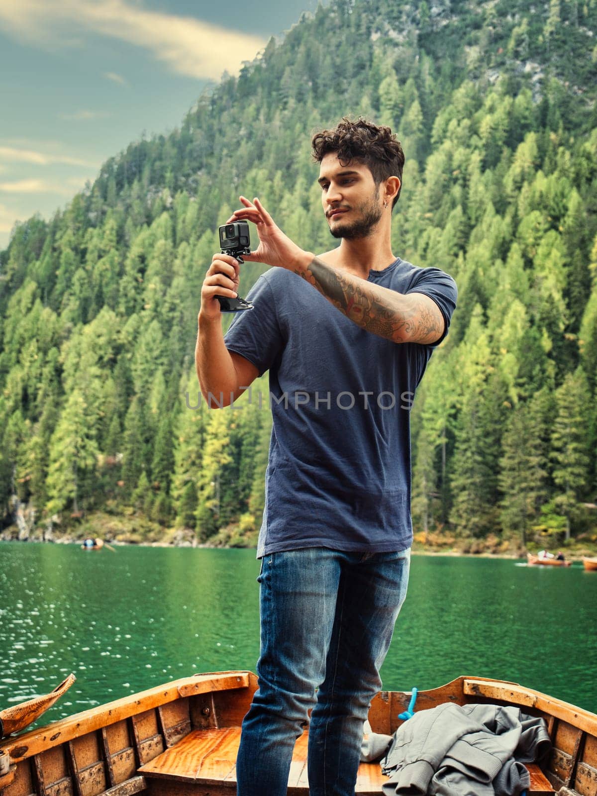 A man standing on a boat holding a camera. Photo of a man capturing the breathtaking beauty of the Dolomites from a boat in Italy