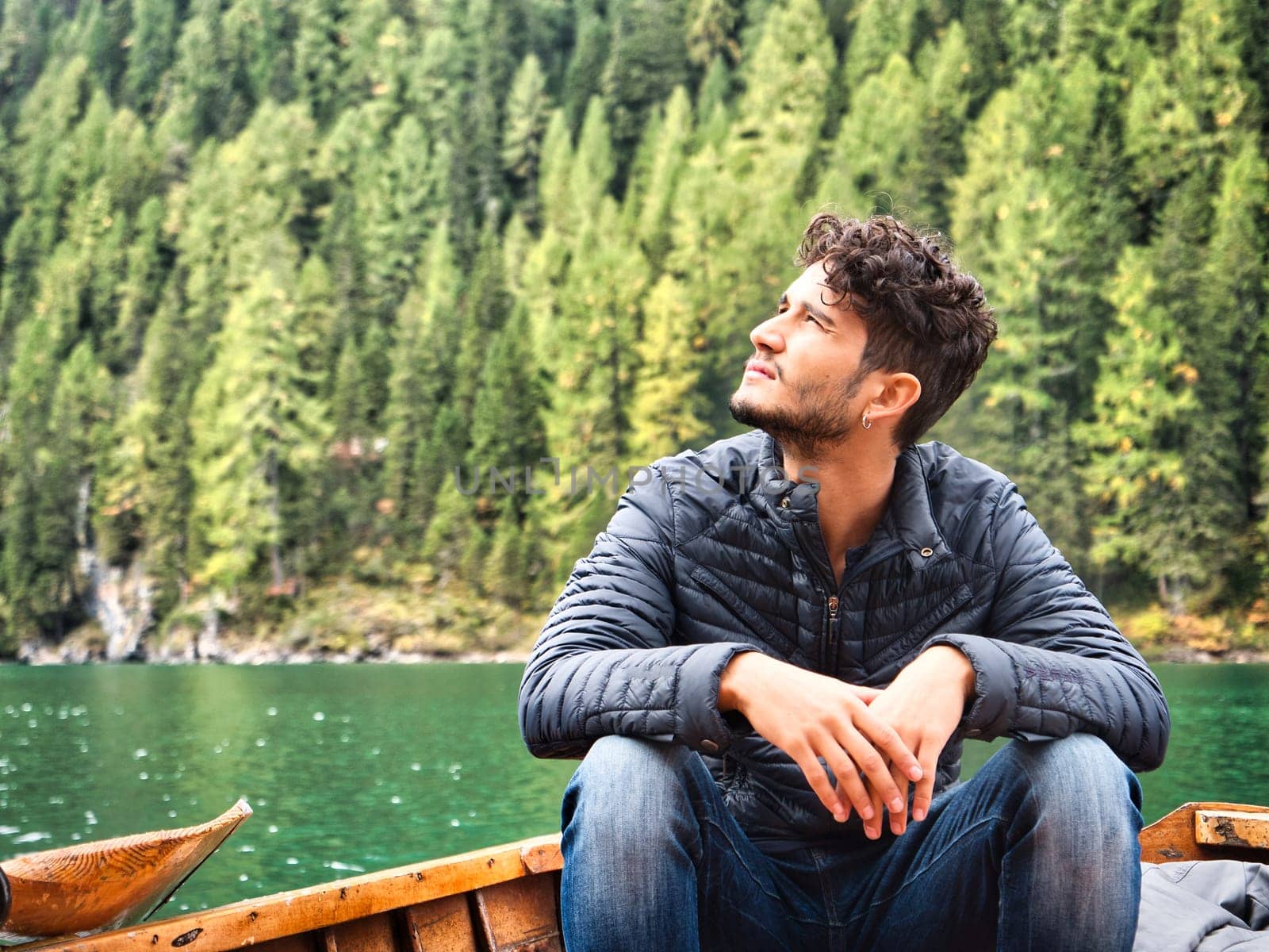 A man sitting in a boat on a lake. Photo of a man peacefully enjoying the serenity of a scenic lake in the beautiful Italian Dolomites