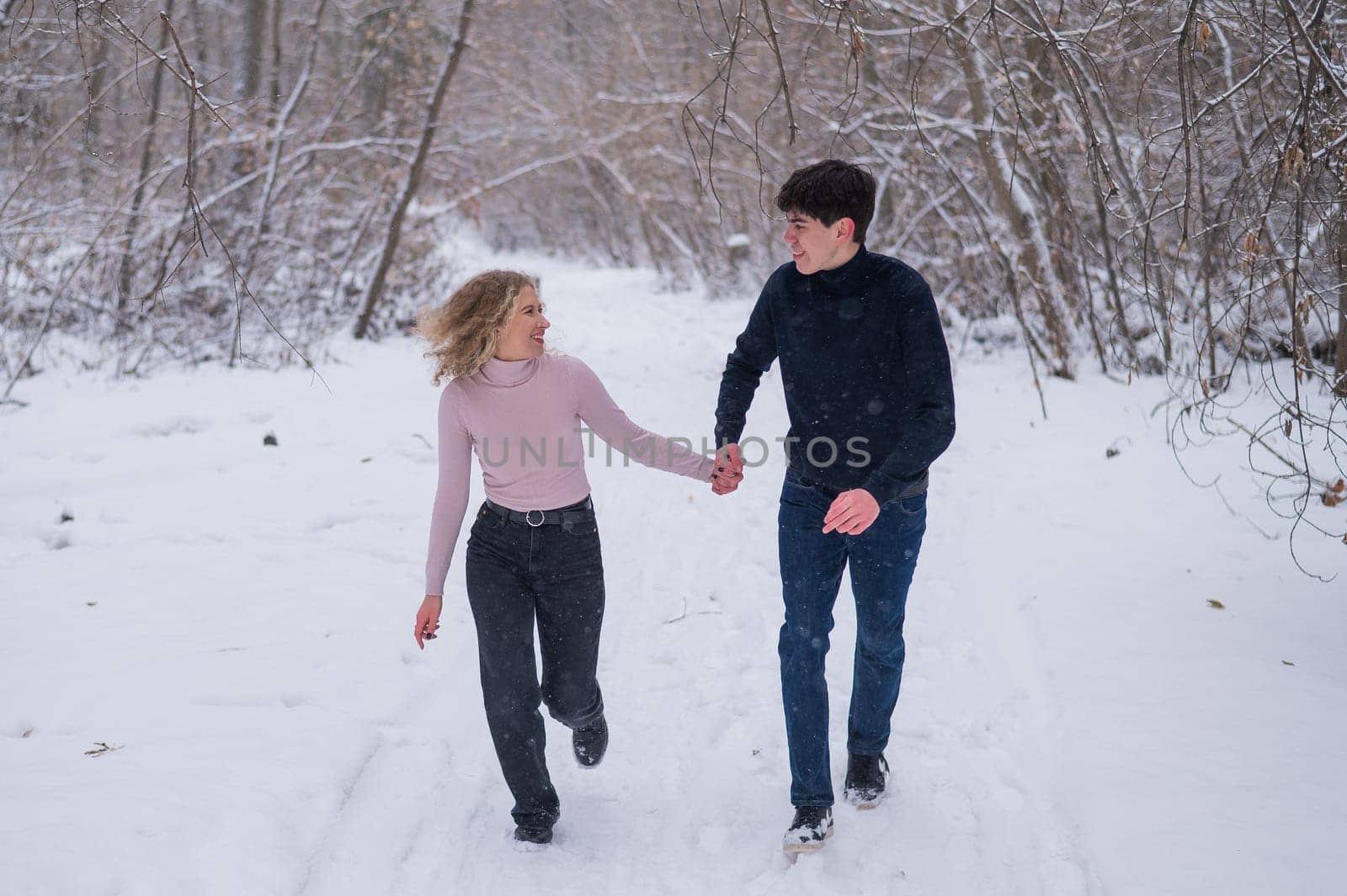 A young couple walks in the park in winter without jackets