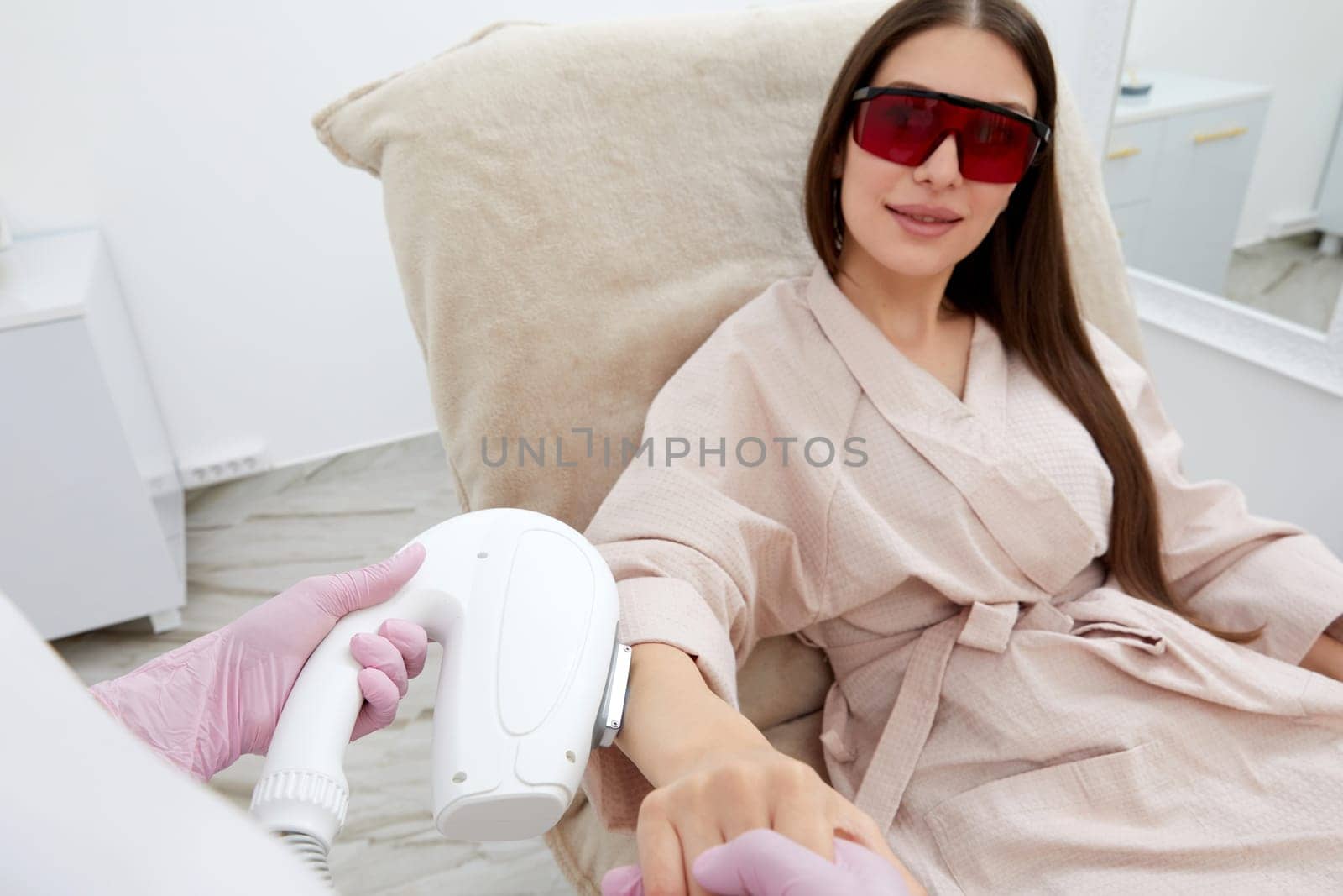 Woman lies peacefully at salon during laser hair removal treatment on arms by Mariakray