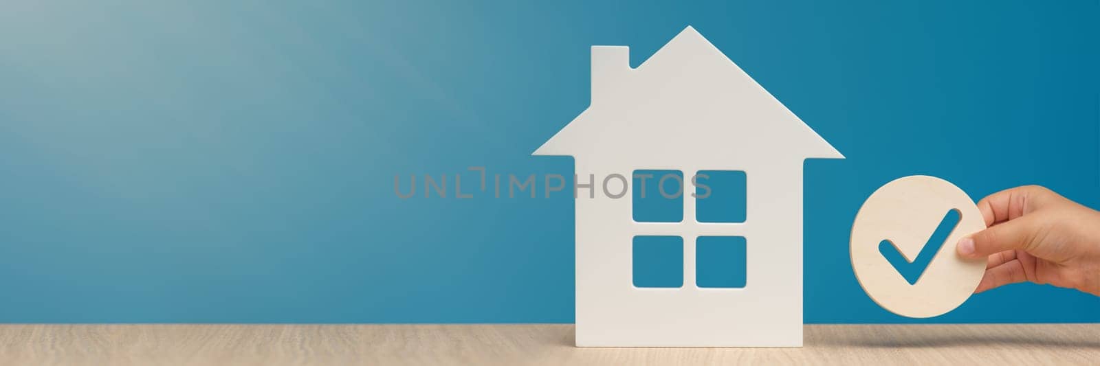 Real estate mortgage approval. Check mark icon in hand and house model as a symbol of a successful real estate purchase or sale deal. Banner with copy space. by SERSOL