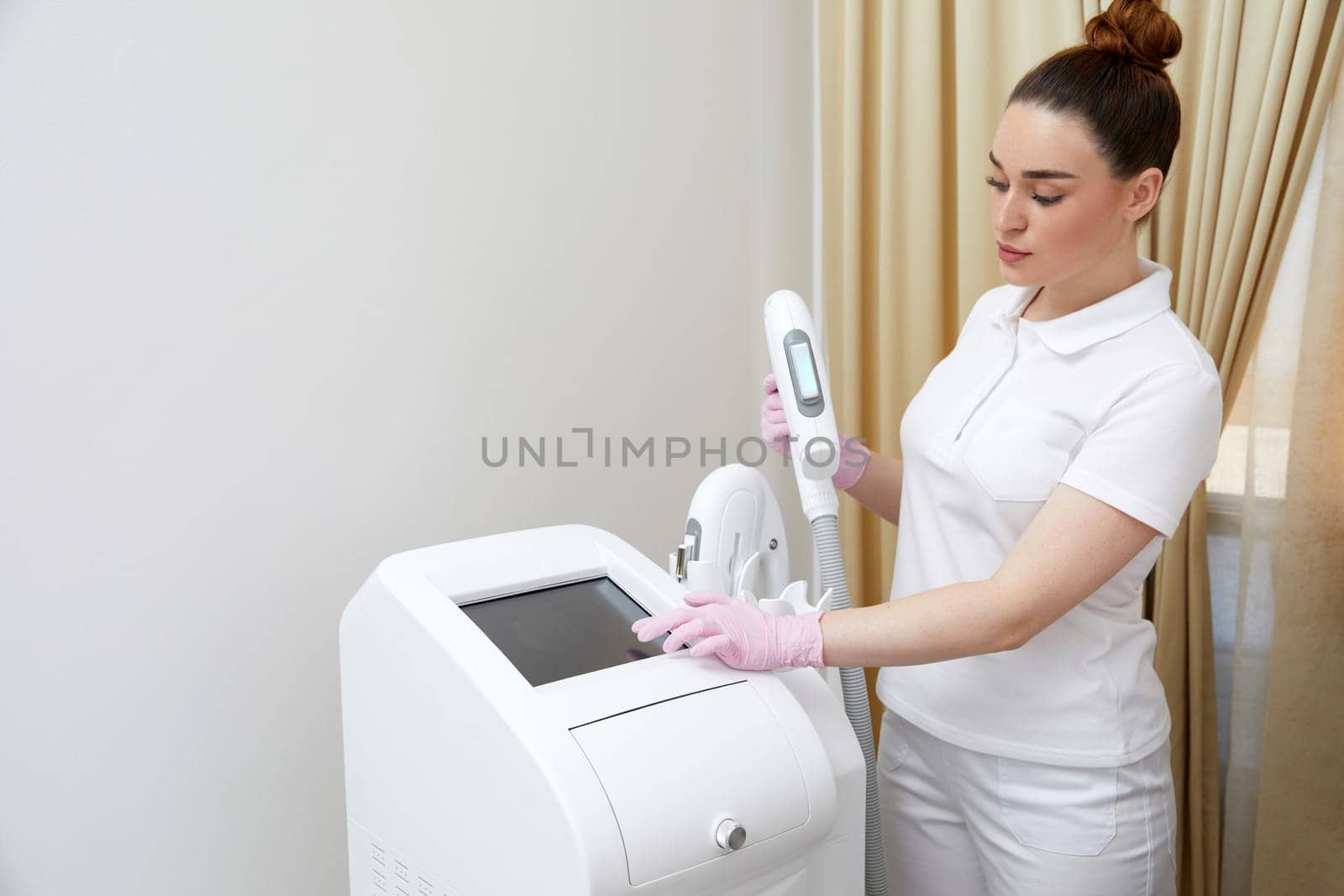 Delving into the preparatory phase, a cosmetologist tweaks and readies the laser machine for a forthcoming treatment