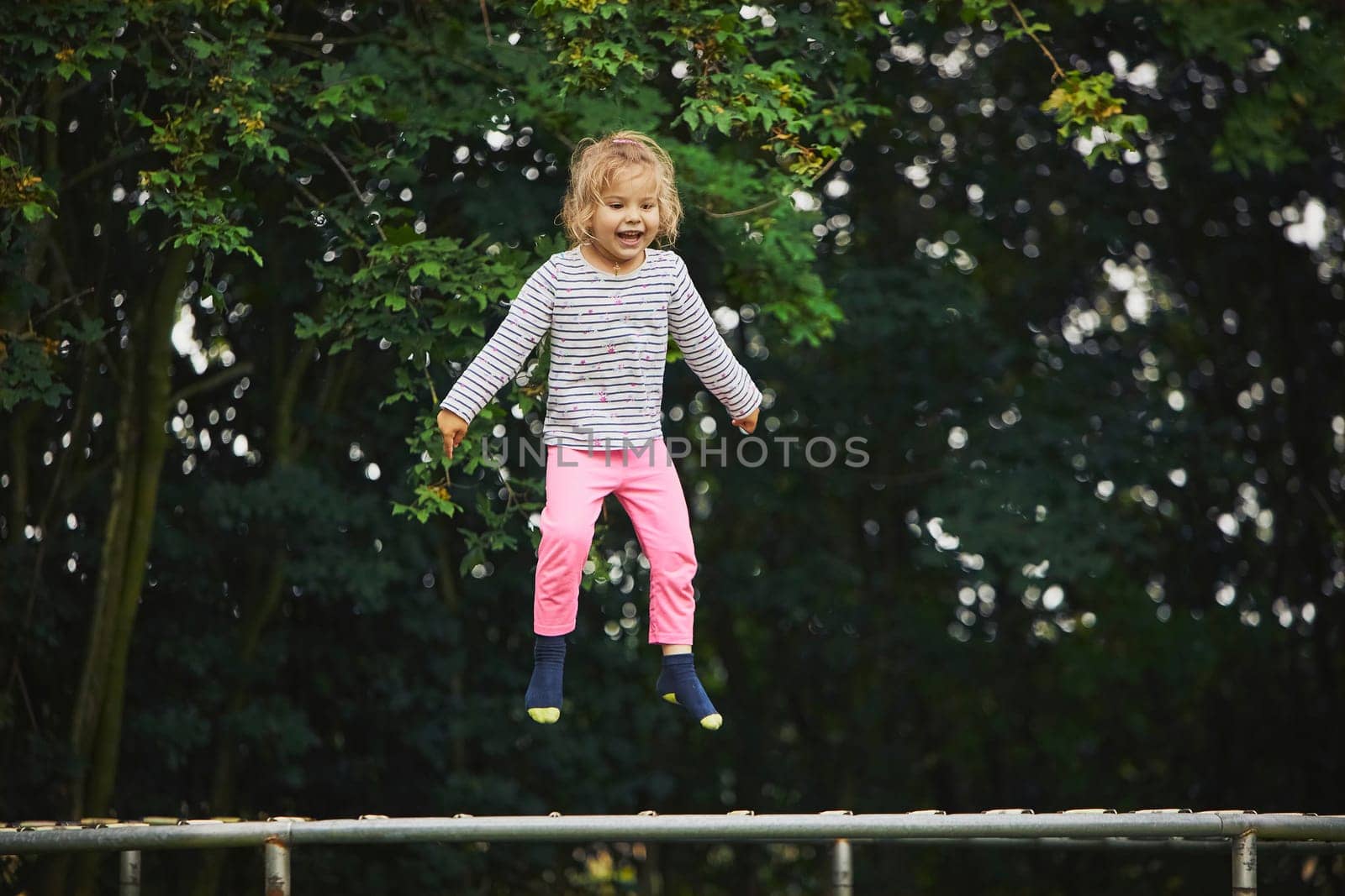 Child jumping on a trampoline in the evening garden in Denmark.